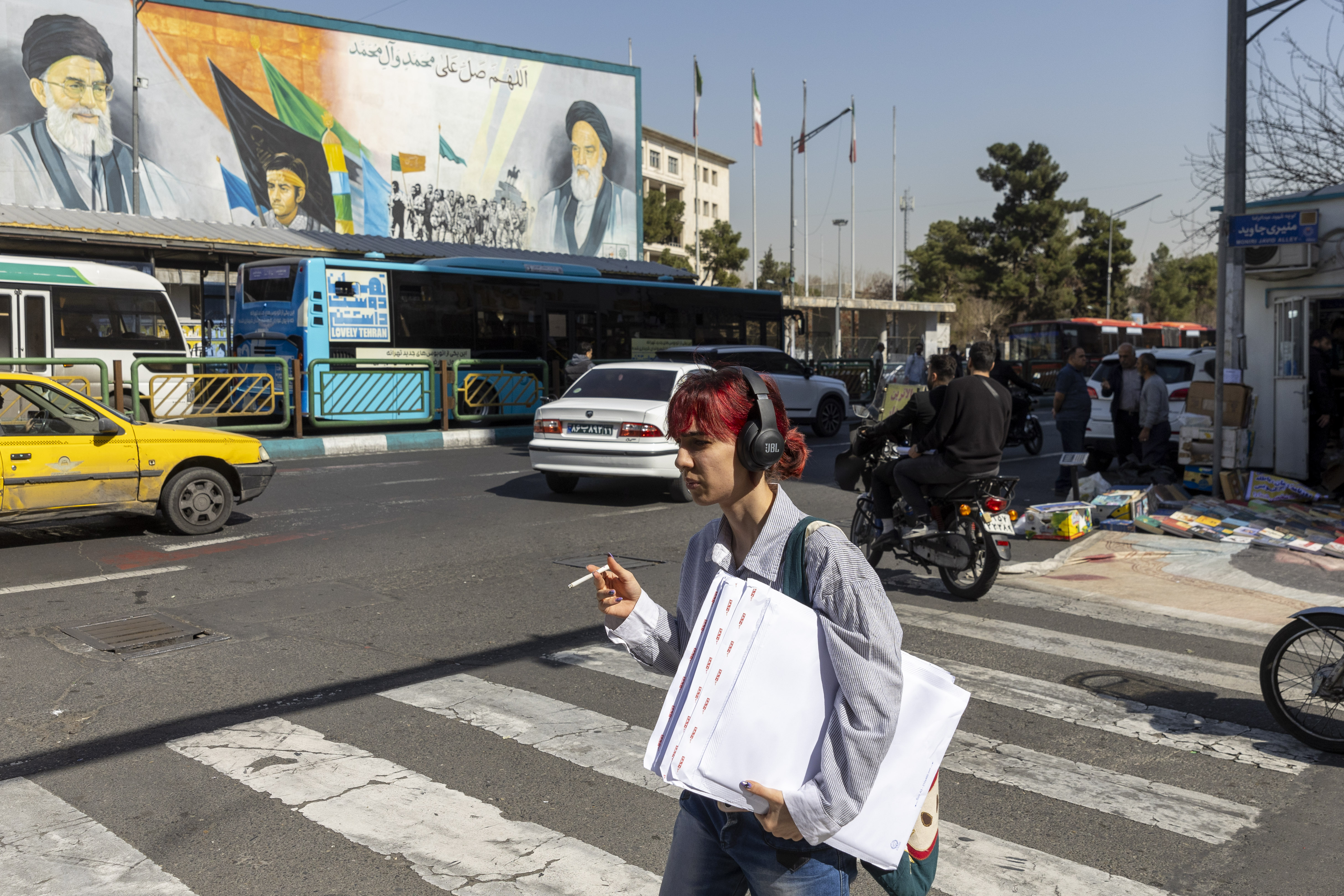 TEHRAN, IRAN - FEBRUARY 21: An Iranian woman walks across a main street in Tehran with the background of a large poster of Iran's supreme leaders, Ayatollah Ali Khamenei and Ayatollah Ruhollah Khomeini on February 21, 2026 in Tehran, Iran. In recent weeks, the United States has moved vast numbers of military vessels and aircraft to Europe and the Middle East, heightening speculation that it intended to strike Iran. (Photo by Majid Saeedi/Getty Images)