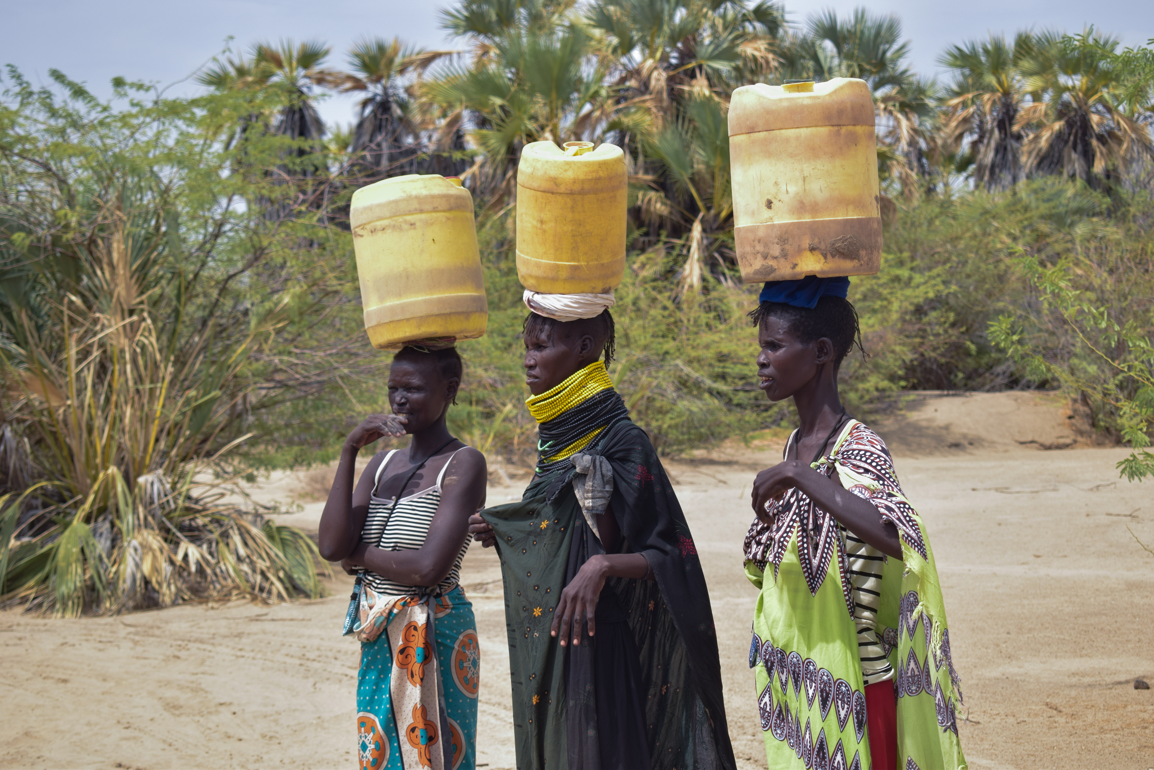 Women carry water canisters on their heads.