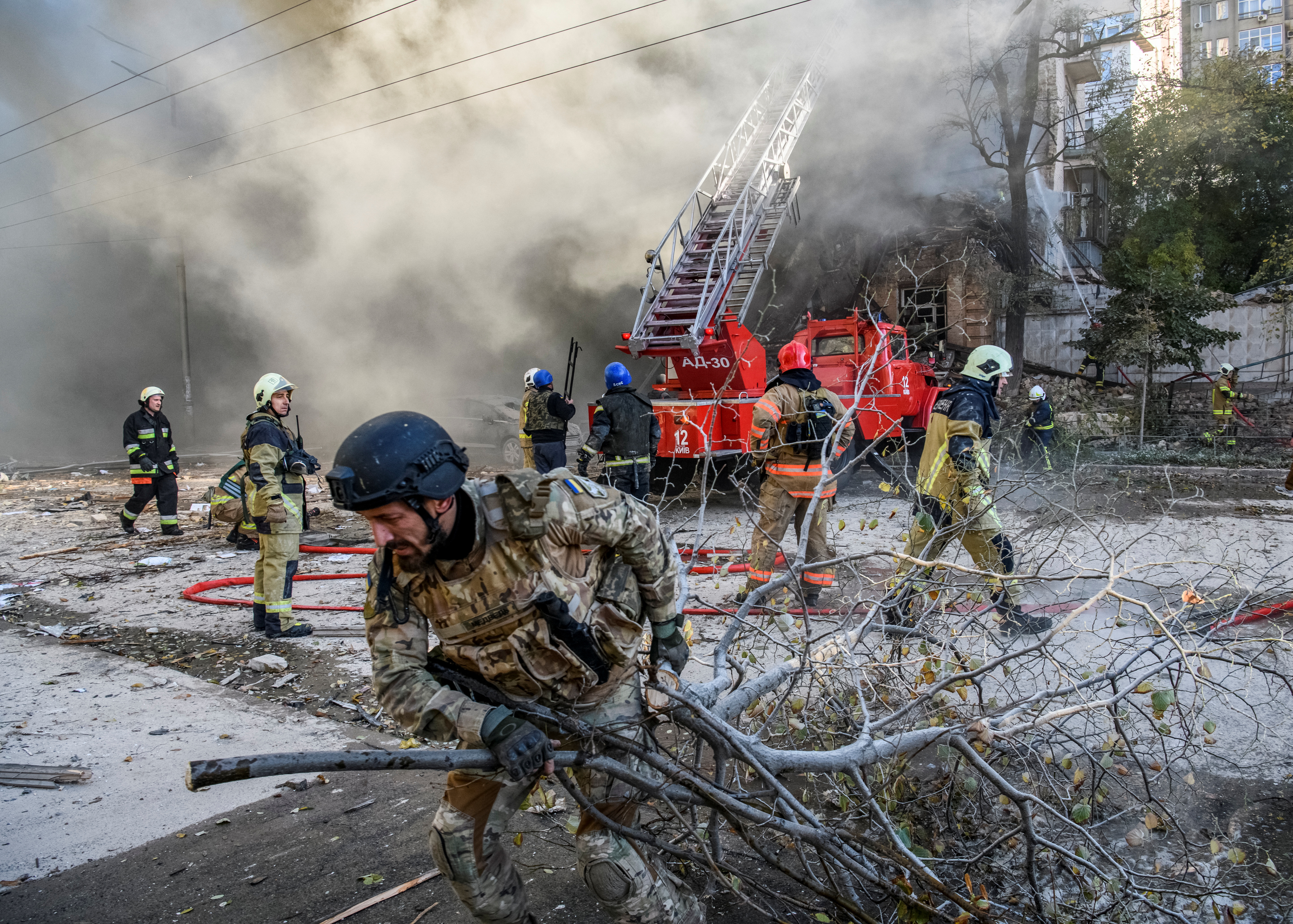 Firefighters help a local woman evacuate from a residential building destroyed by a Russian drone strike, which local authorities consider to be Iranian-made unmanned aerial vehicles (UAVs) Shahed-136, amid Russia's attack on Ukraine, in Kyiv, Ukraine October 17, 2022. REUTERS/Vladyslav Musiienko