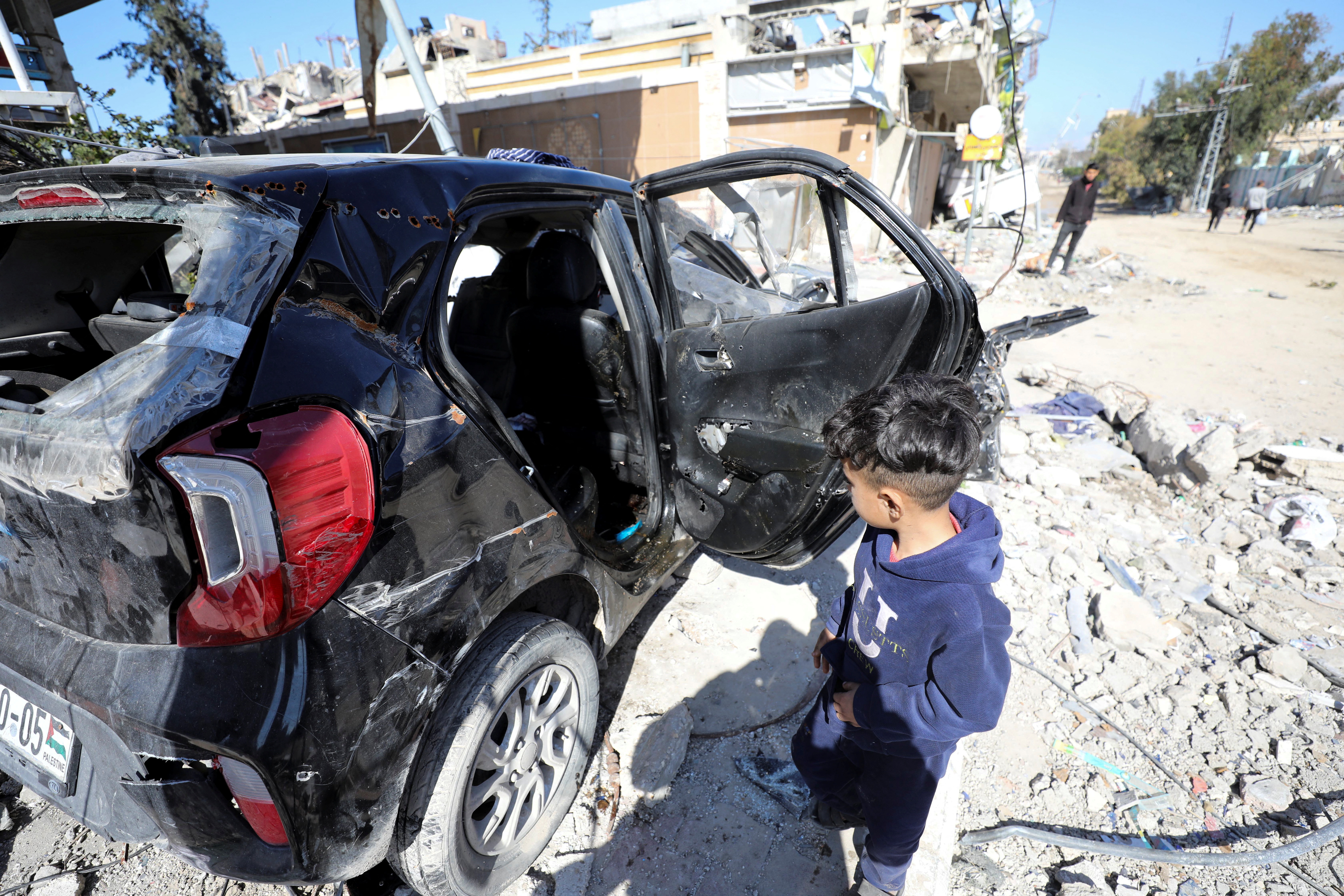 A child walks near a car where the body of Palestinian girl Hind Rajab, 6, who begged Gaza rescuers to send help after being trapped by Israeli military fire, was found along with the bodies of five of her family members as two ambulance workers who had gone to save her were killed, amid the ongoing conflict between Israel and Hamas, in Gaza City, February 10, 2024. REUTERS/Stringer