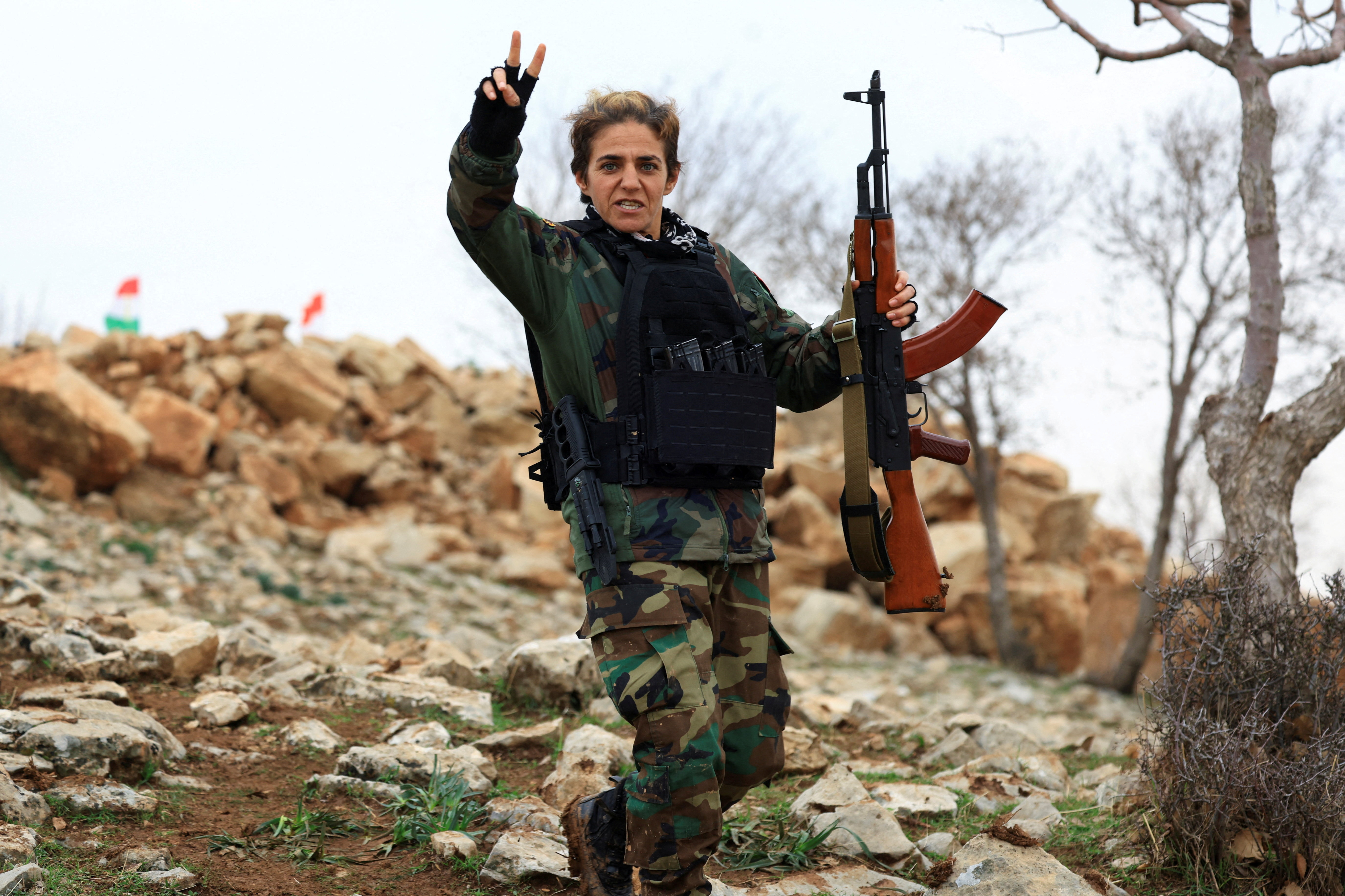 A fighter from the Kurdistan Freedom Party (PAK) carries a rifle and gestures while standing on rocky terrain, at a training session at a base near Erbil, Iraq February 12, 2026. [Thaier Al-Sudani/Reuters]