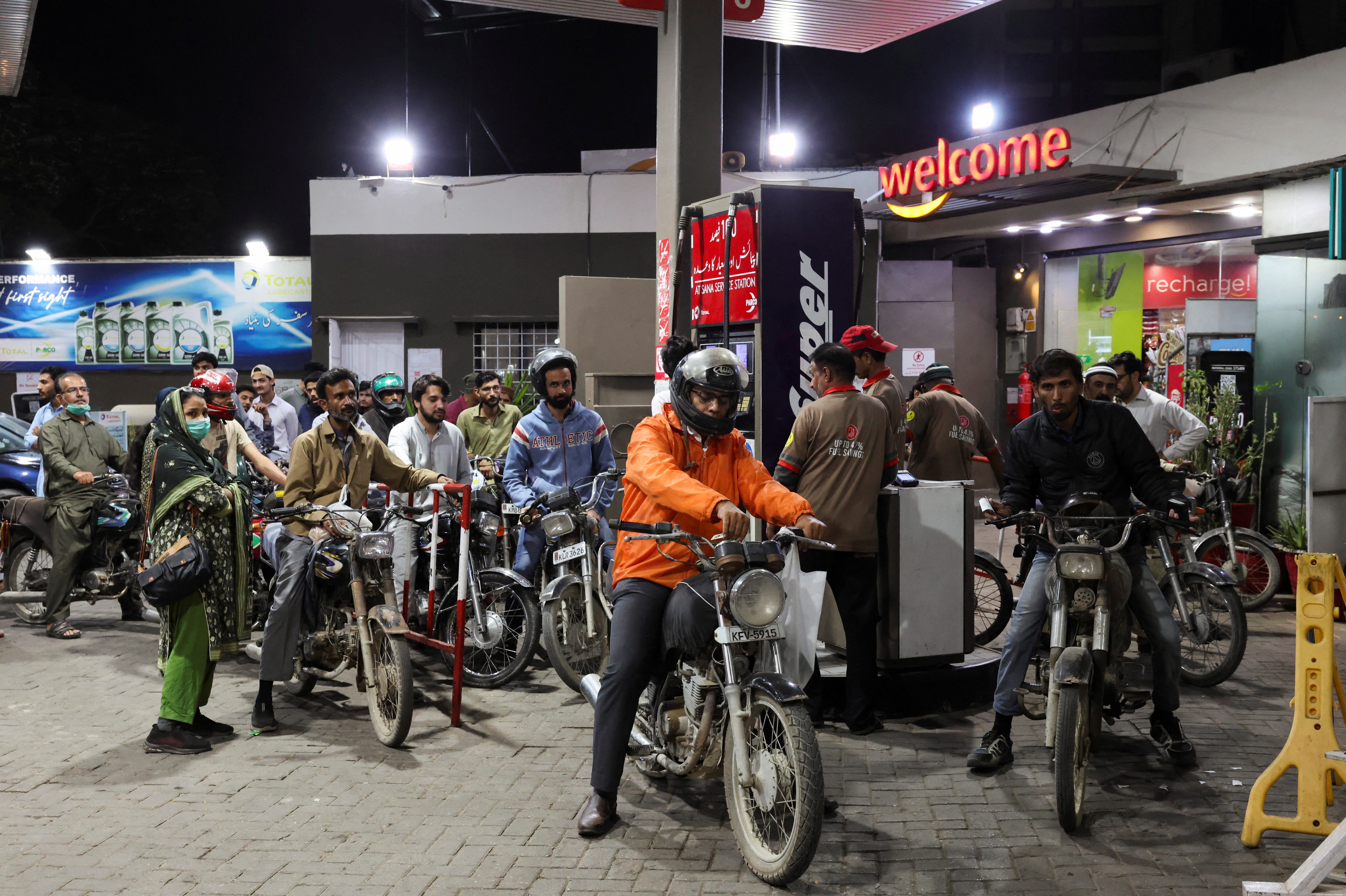 People wait for their turn to get fuel at a petrol station.