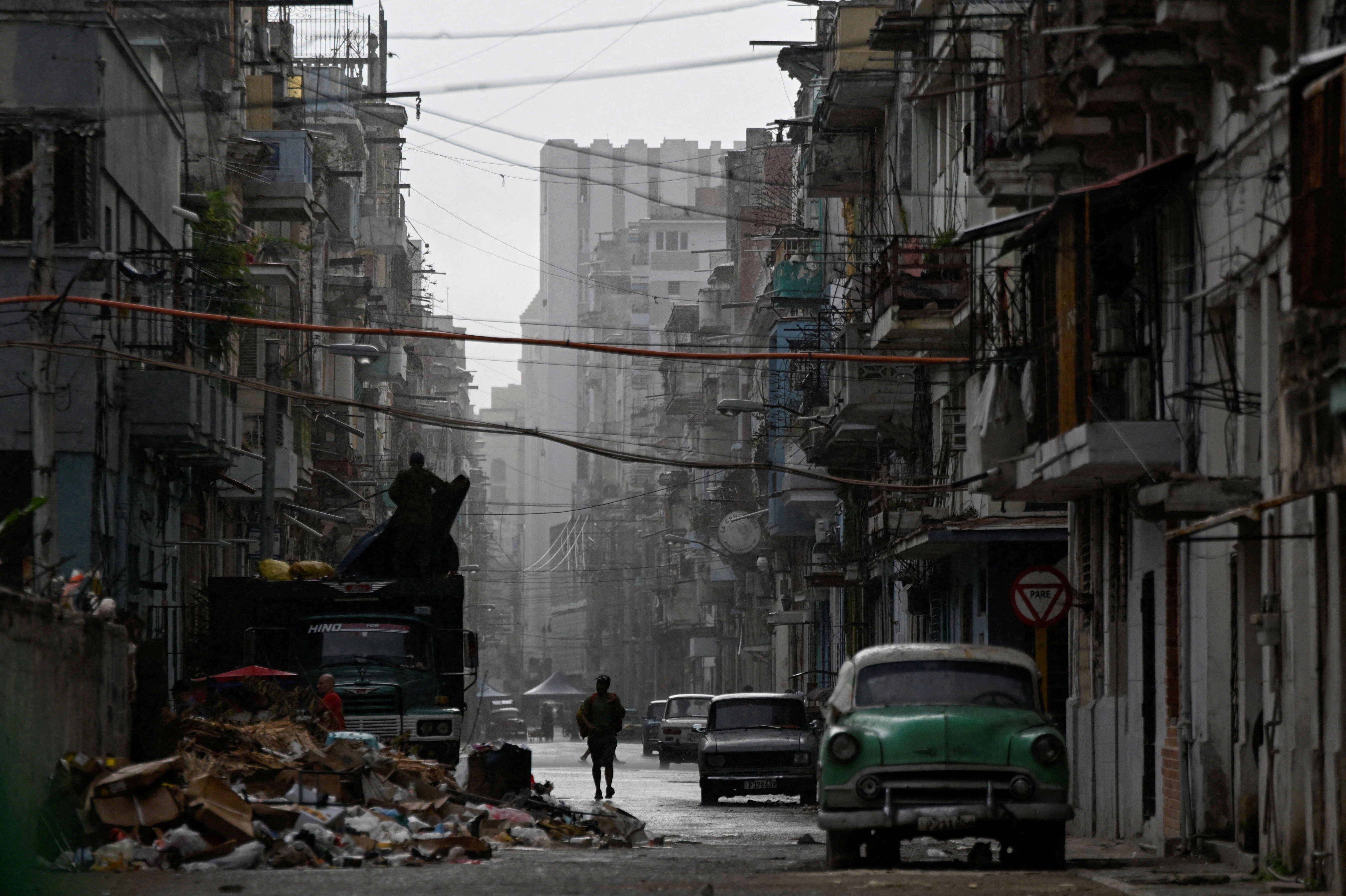 A man walks on a street in the rain as Cuba reconnected its electrical grid across much of the island