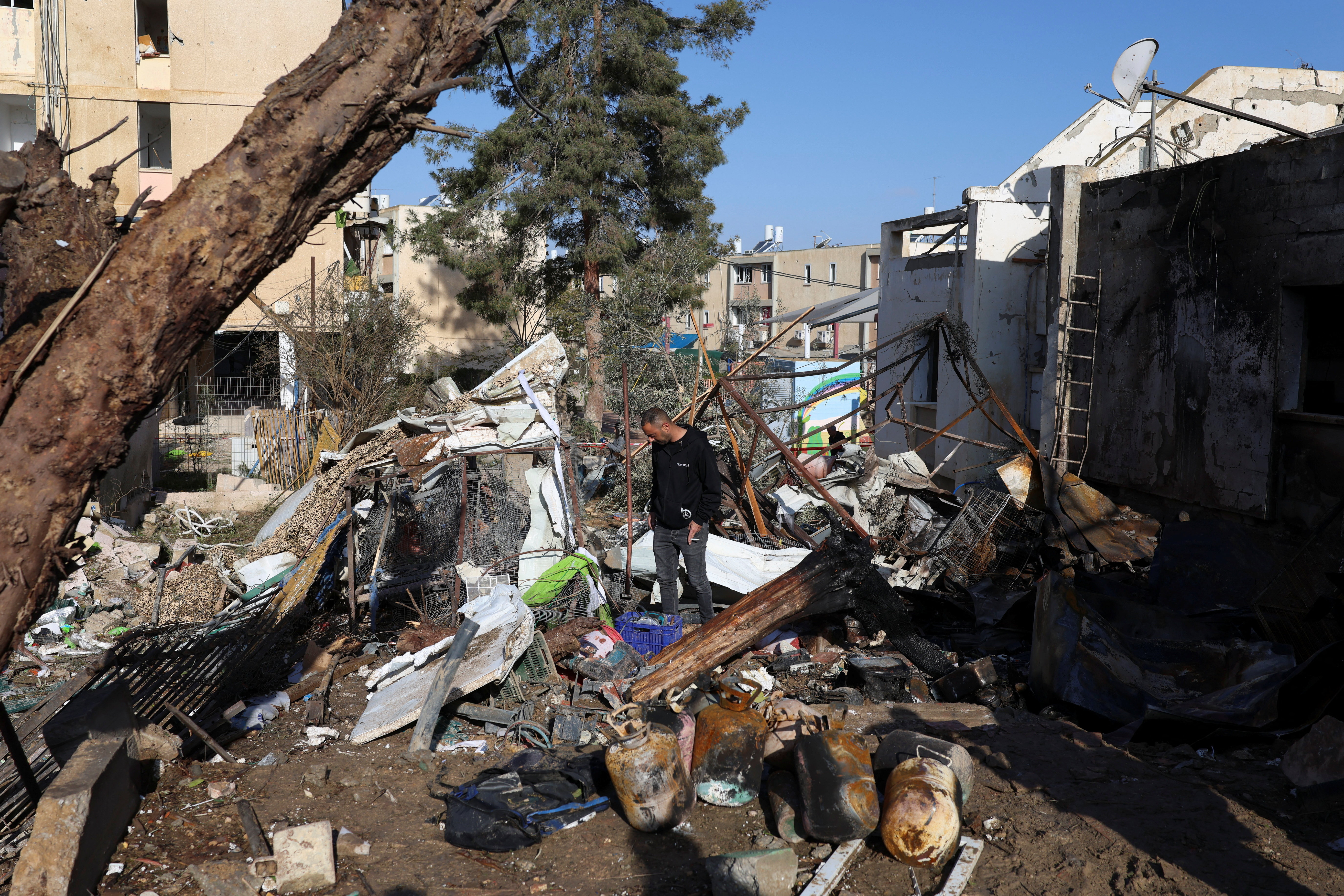 People, including Israeli security personnel, stand at a damaged area following a night of Iranian missile strikes which injured