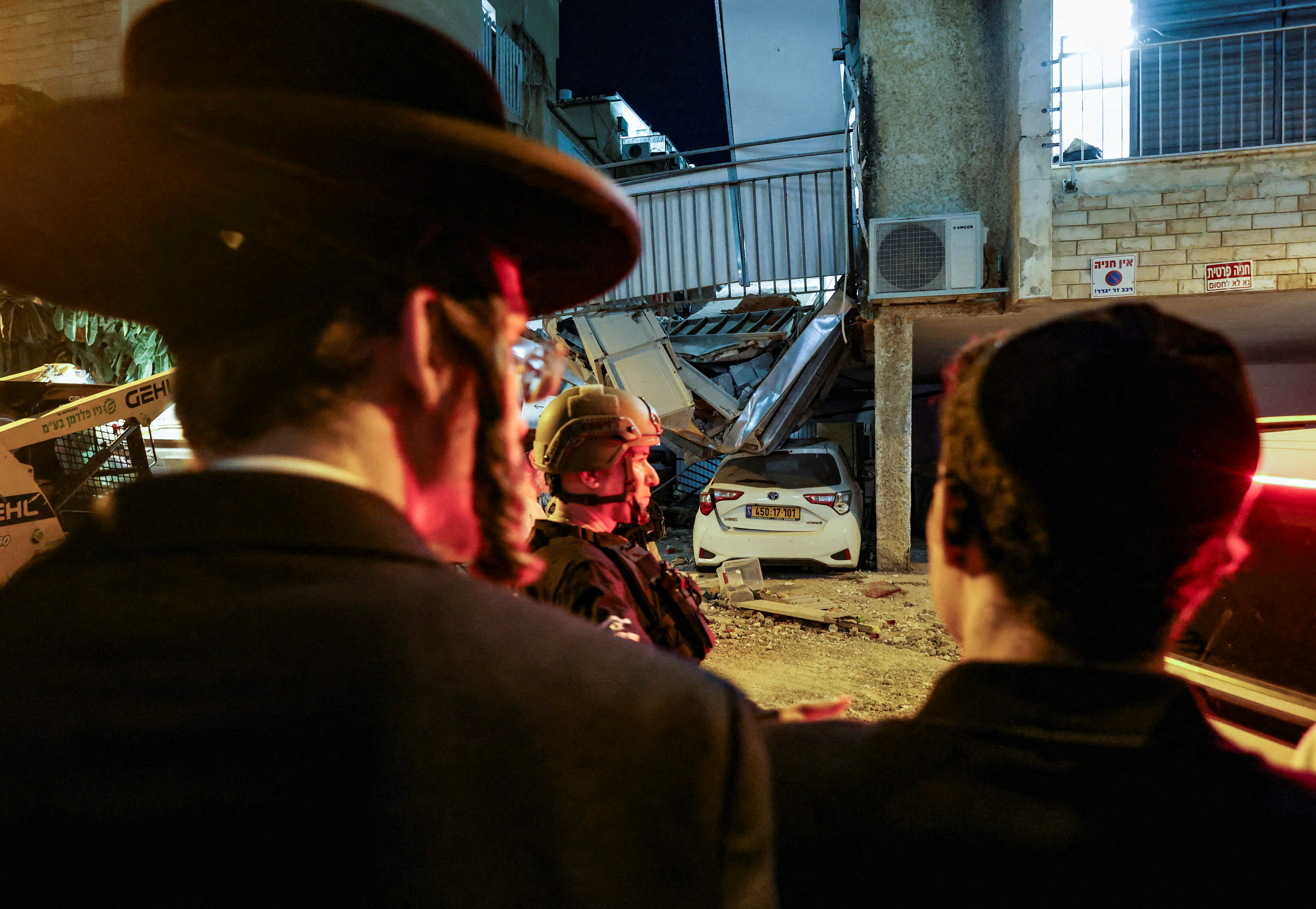 People look on as emergency personnel respond following Iranian missile barrages in central Israel, amid the U.S.-Israel conflict with Iran, March 24, 2026.