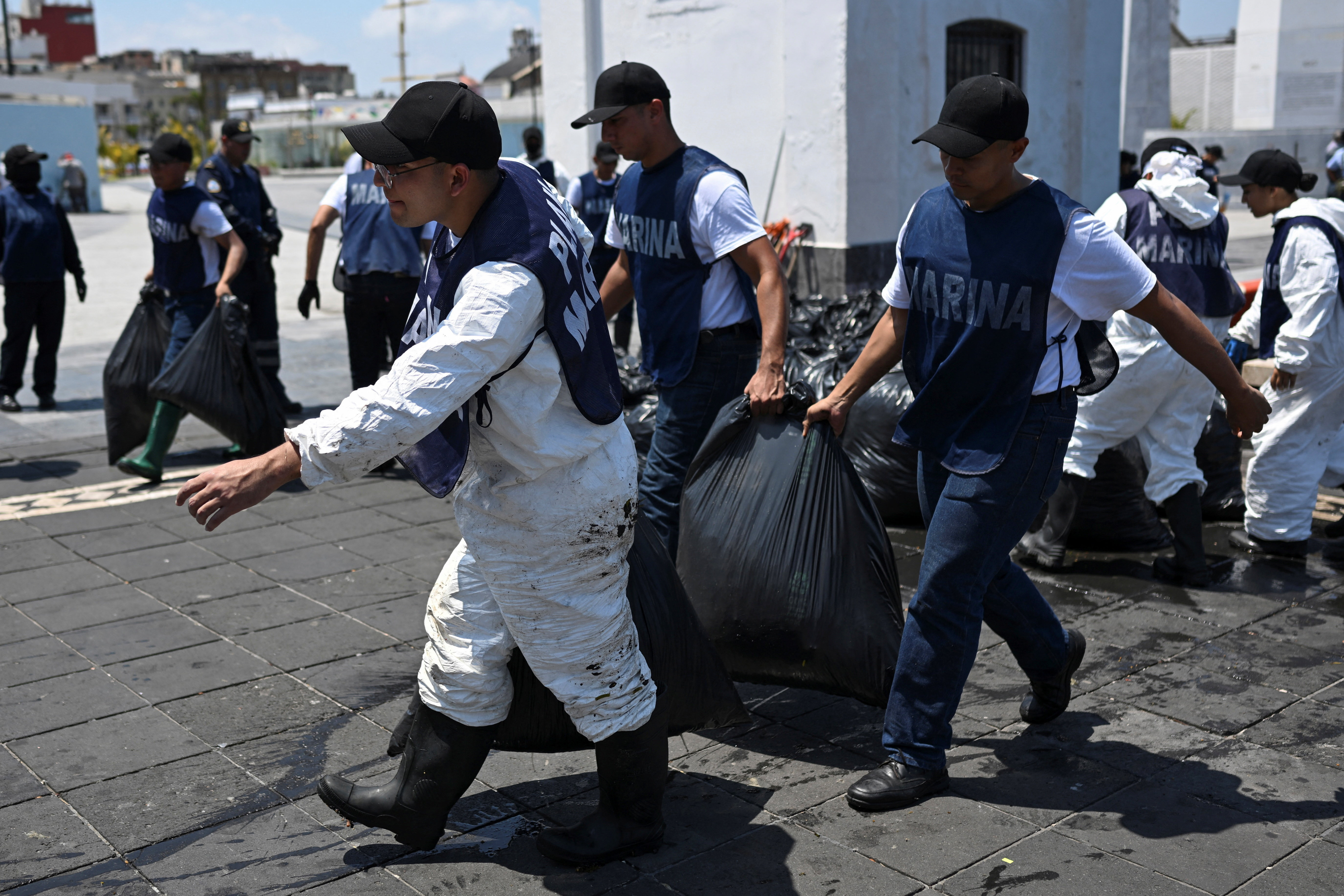 Members of the Mexican Navy remove tar-stained seaweed from the shoreline.