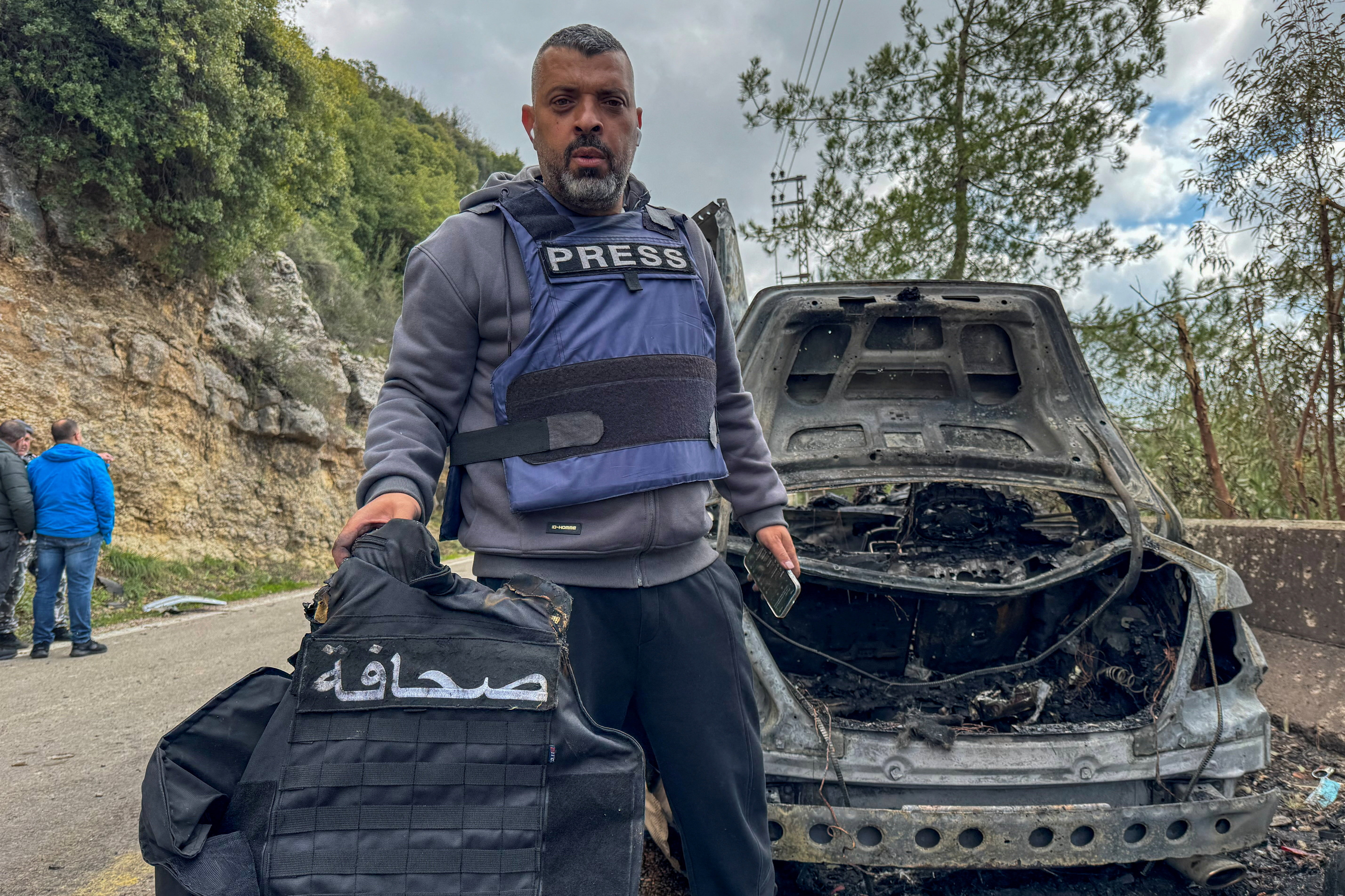 Al Mayadeen journalist Jamal Al-Gharabi holds a press vest next to a car destroyed by a targeted Israeli strike that killed Lebanese journalists Al Mayadeen reporter Fatima Ftouni and cameraman Mohammed Ftouni, and Al Manar reporter Ali Shaib, amid escalating hostilities between Israel and Hezbollah, as the U.S.-Israeli conflict with Iran continues, in Jezzine, in southern Lebanon, March 28, 2026. The sign on the vest reads "Press". Picture taken with a mobile phone. REUTERS/Ali Hankir TPX IMAGES OF THE DAY REFILE - REPHRASING CAPTION TO ADD IDs