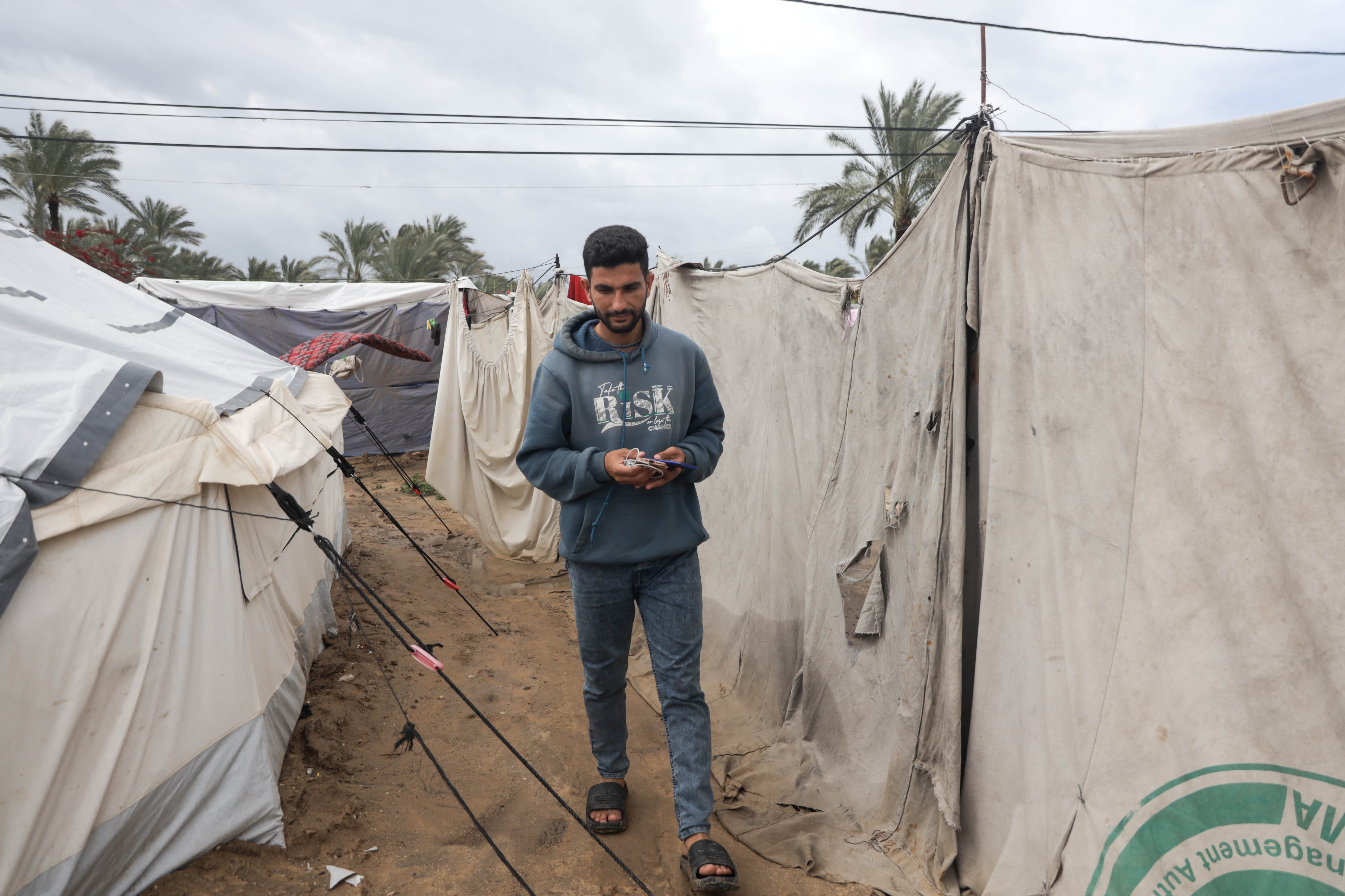 Abdel Karim Salman heads daily to the charging station to charge his phone and his wife’s phone, which they use as a source of light in their tent throughout the night [Abdelhakim Abu Riash/ Al Jazeera]