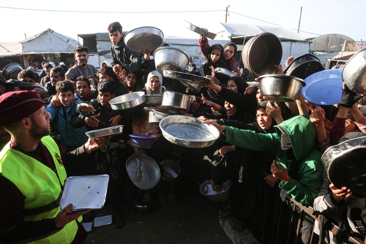Displaced Palestinians jostle for food at a food bank in Khan Younis, Gaza Strip