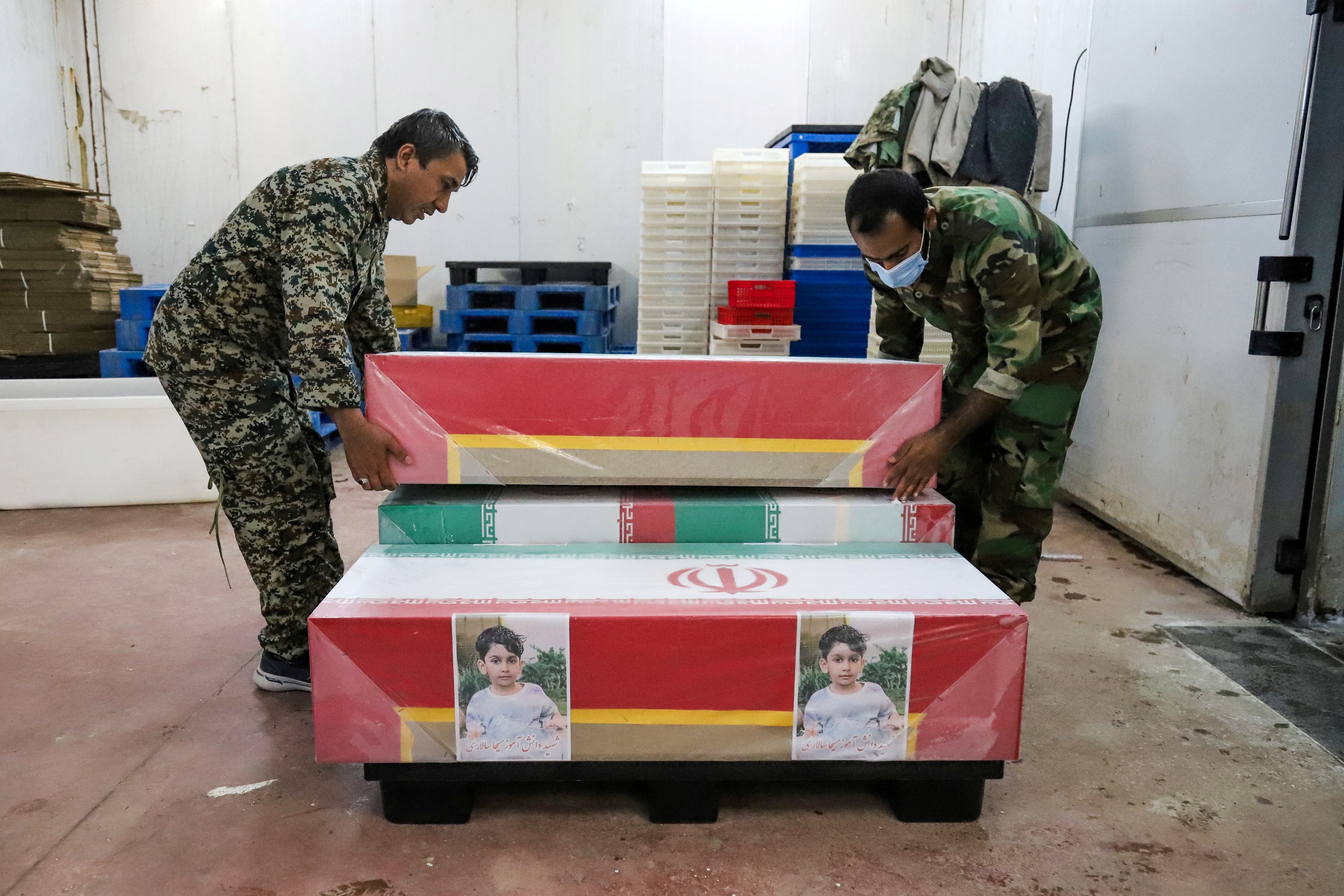 Men lift casket wrapped in Iranian flag
