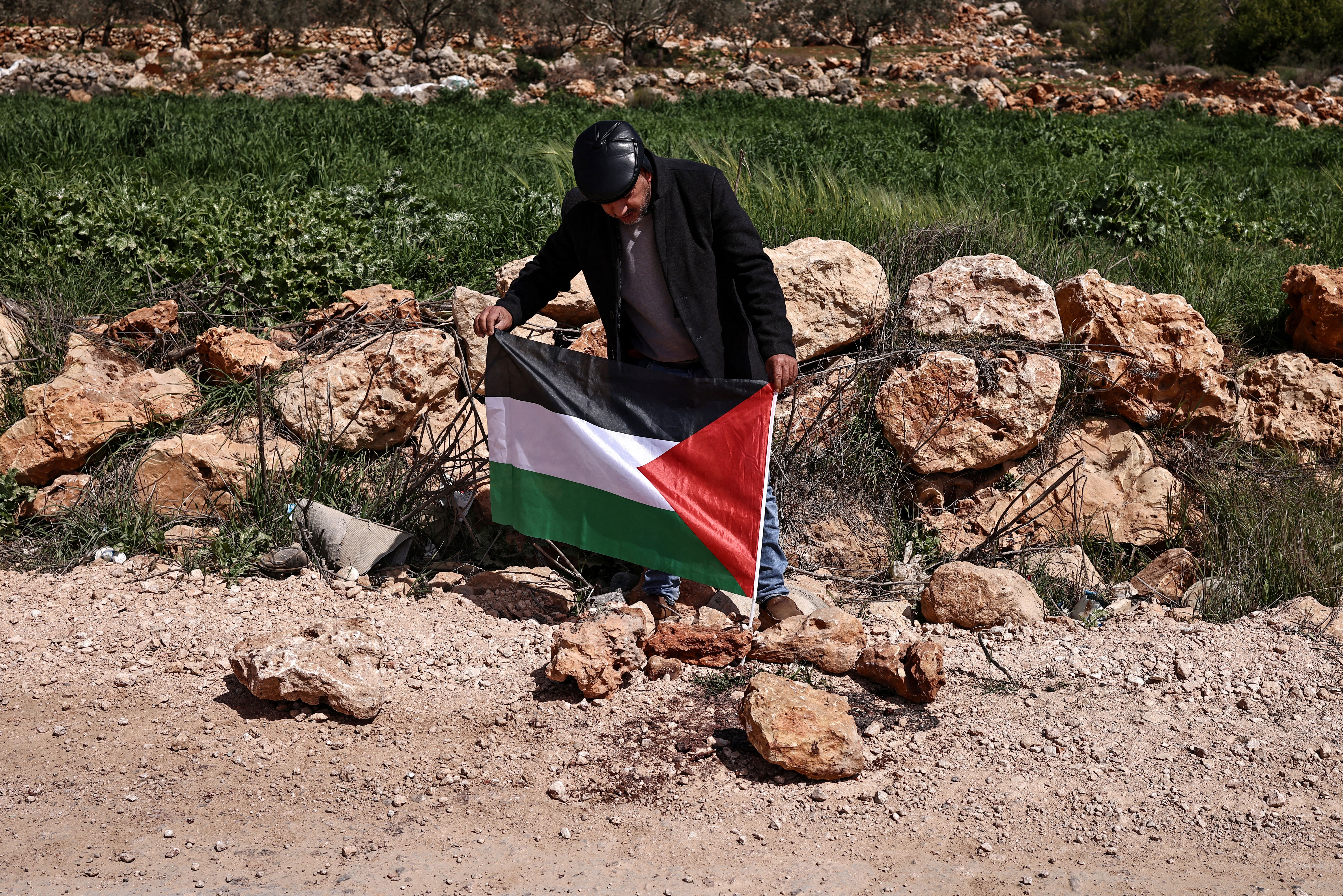 A Palestinian flag is placed at the site where a Jewish settlers' attack killed 3 Palestinians and injured 7 others on March 8, in the village of Abu Falah, northeast of Ramallah in the Israeli-occupied West Bank on March 12, 2026. Excluding Israeli-annexed east Jerusalem, more than 500,000 Israelis live in West Bank settlements and outposts, which are illegal under international law. [Zain Jaafar/AFP]