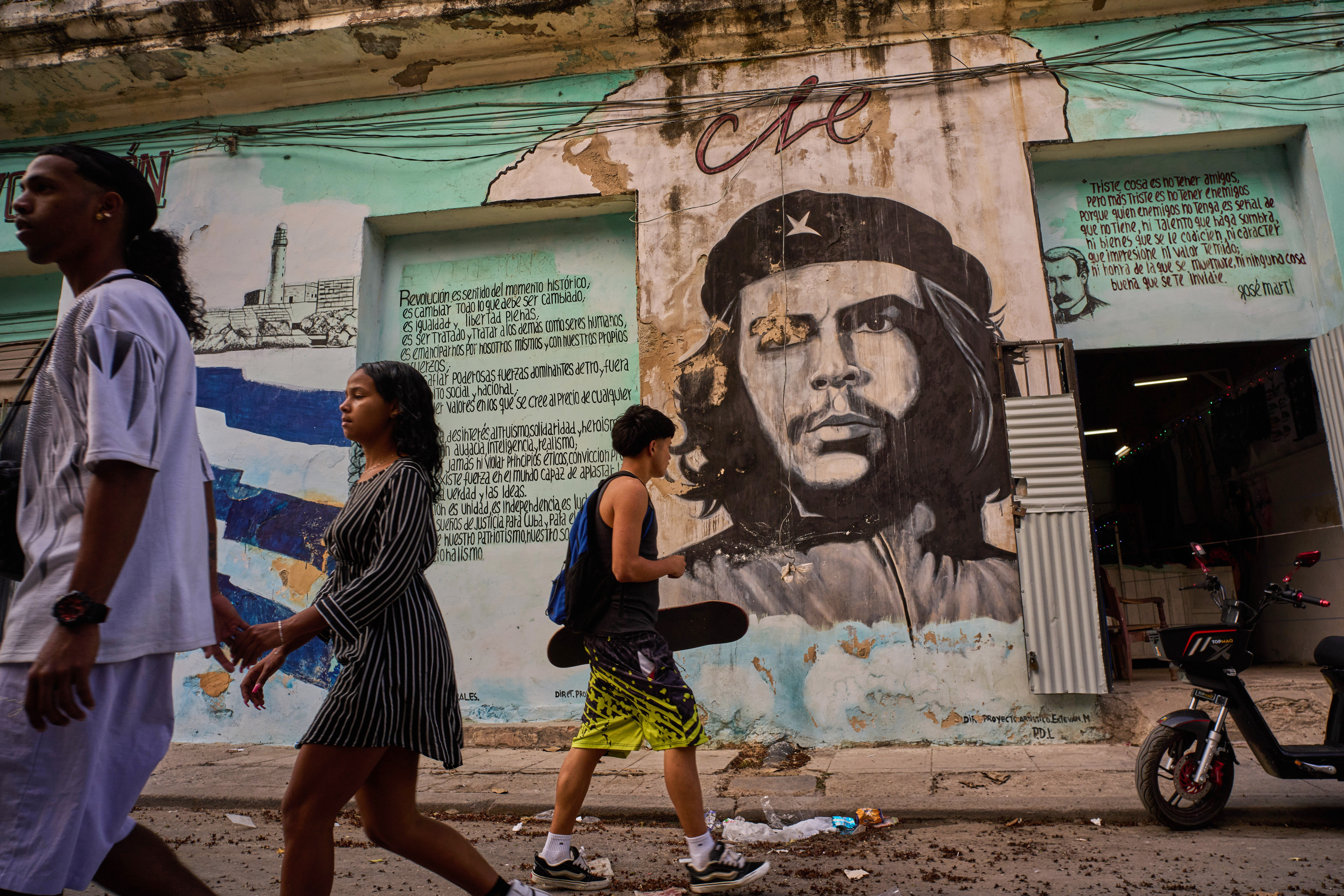 People walk past a mural of Che Guevara in Havana, Cuba