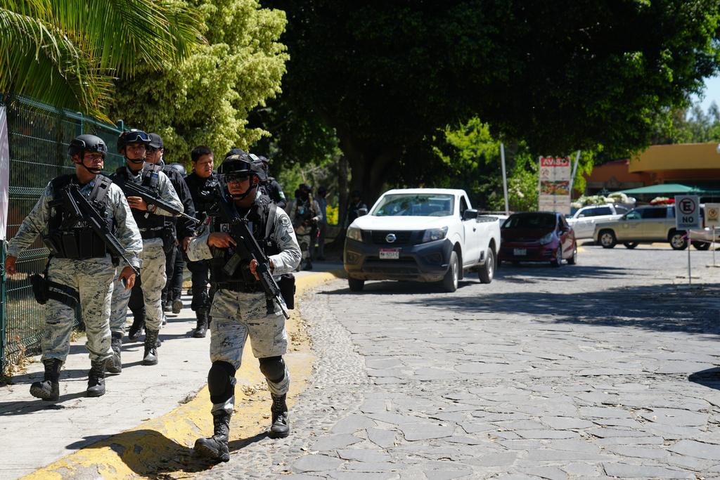 Mexican National Guard members stand in the street with a gun