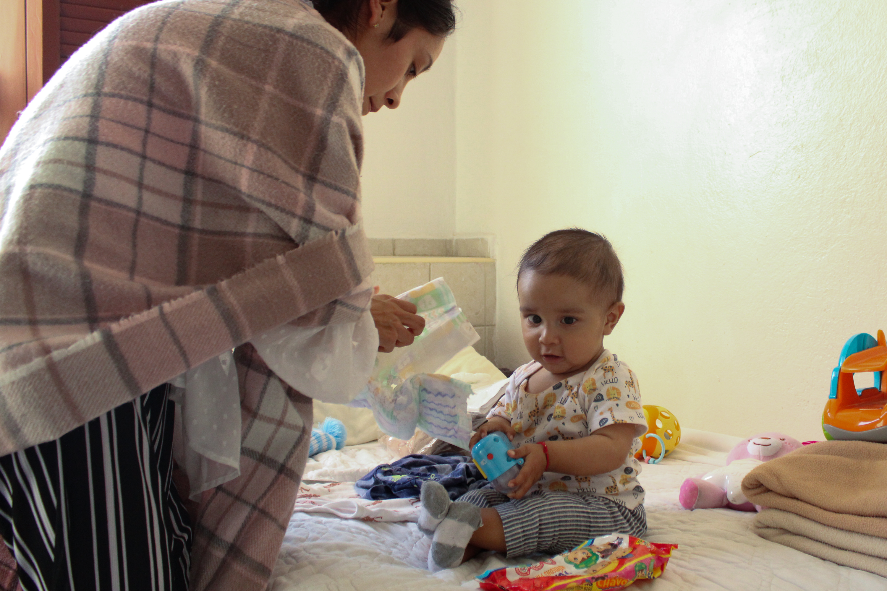In the dormitory, Juan de Jesús sits on the bed waiting as Luisa prepares to change him [Mark Viales/Al Jazeera]
