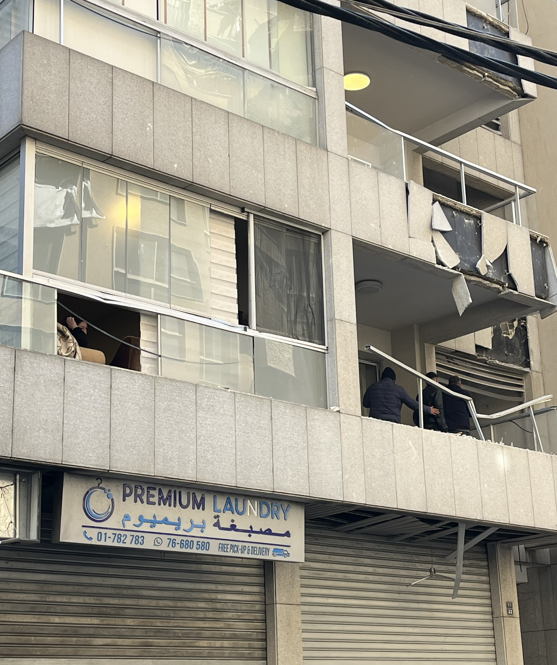 A woman looks on from her damaged apartment, across from the site of attack in the Aisha Bakkar neighbourhood in Beirut. [Justin Salhani/Al Jazeear]