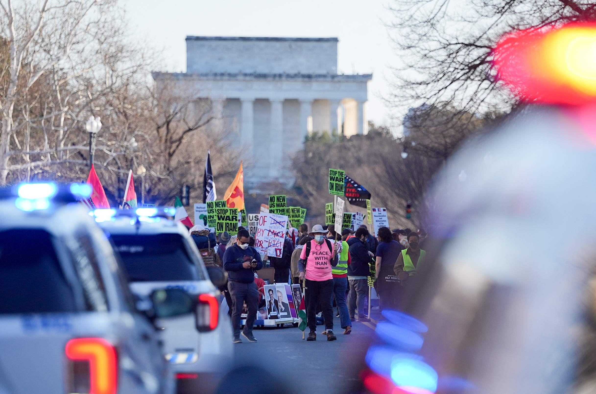 People hold signs condemning the war on Iran as they protest in front of the Lincoln Memorial in Washington, DC, on February 28, 2026.