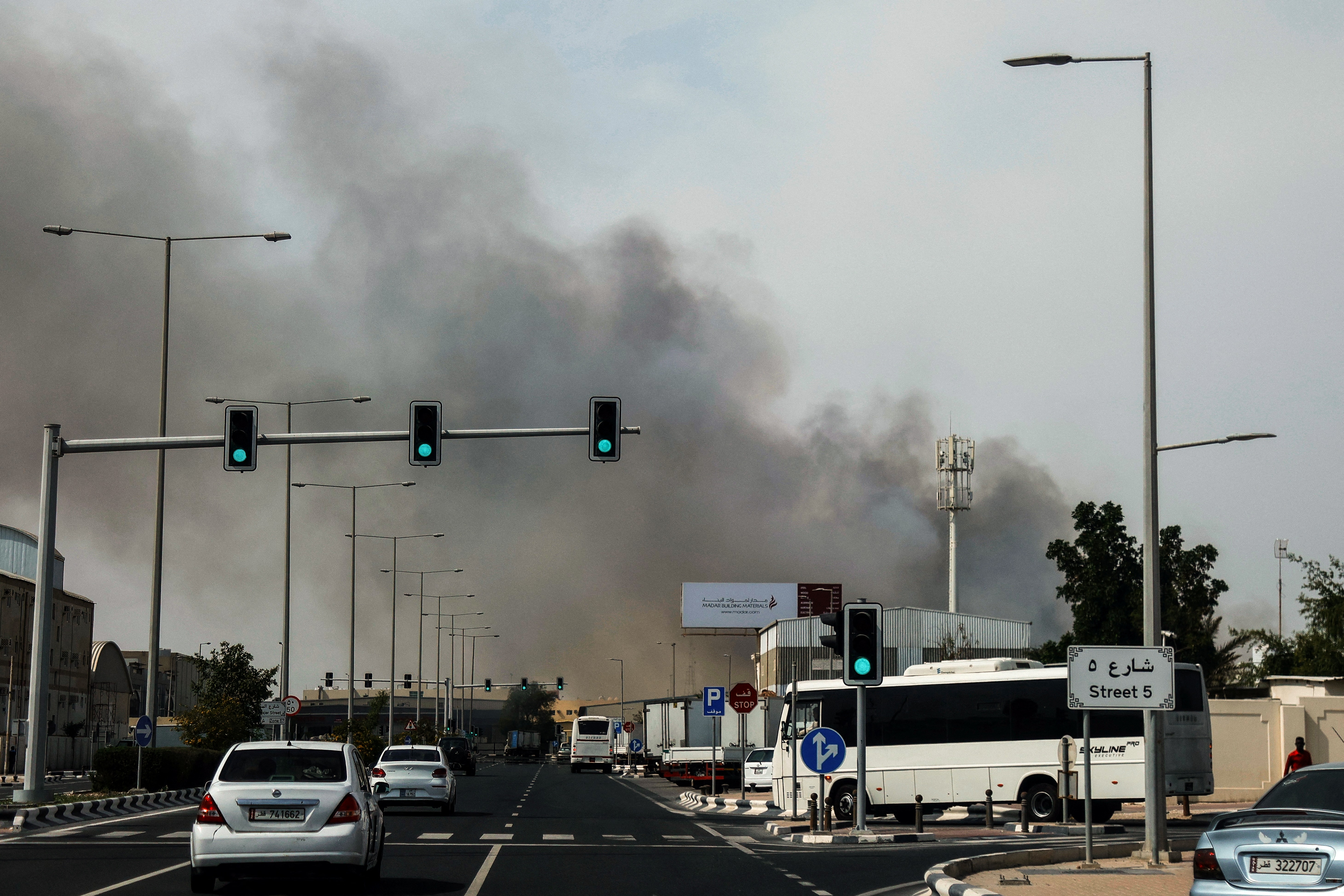 Motorists drive past a plume of smoke rising from a reported Iranian strike in the industrial district of Doha on March 1, 2026.