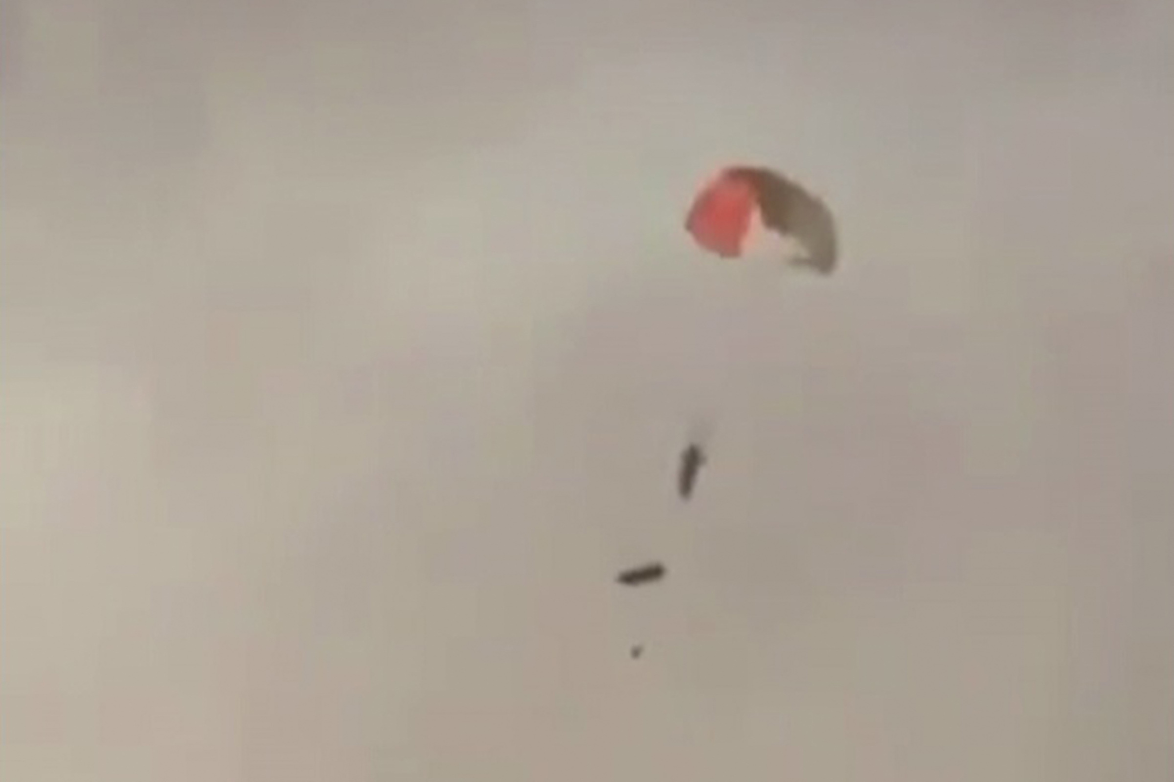 TOPSHOT - This video grab taken from UGC images posted on social media on March 2, 2026, shows a pilot descending from the sky with a parachute near al-Jahra in Kuwait after three US warplanes were mistakenly shot down by Kuwait air defence according to the US Central Command, as Iran presses on with a third day of retaliation in the Gulf.