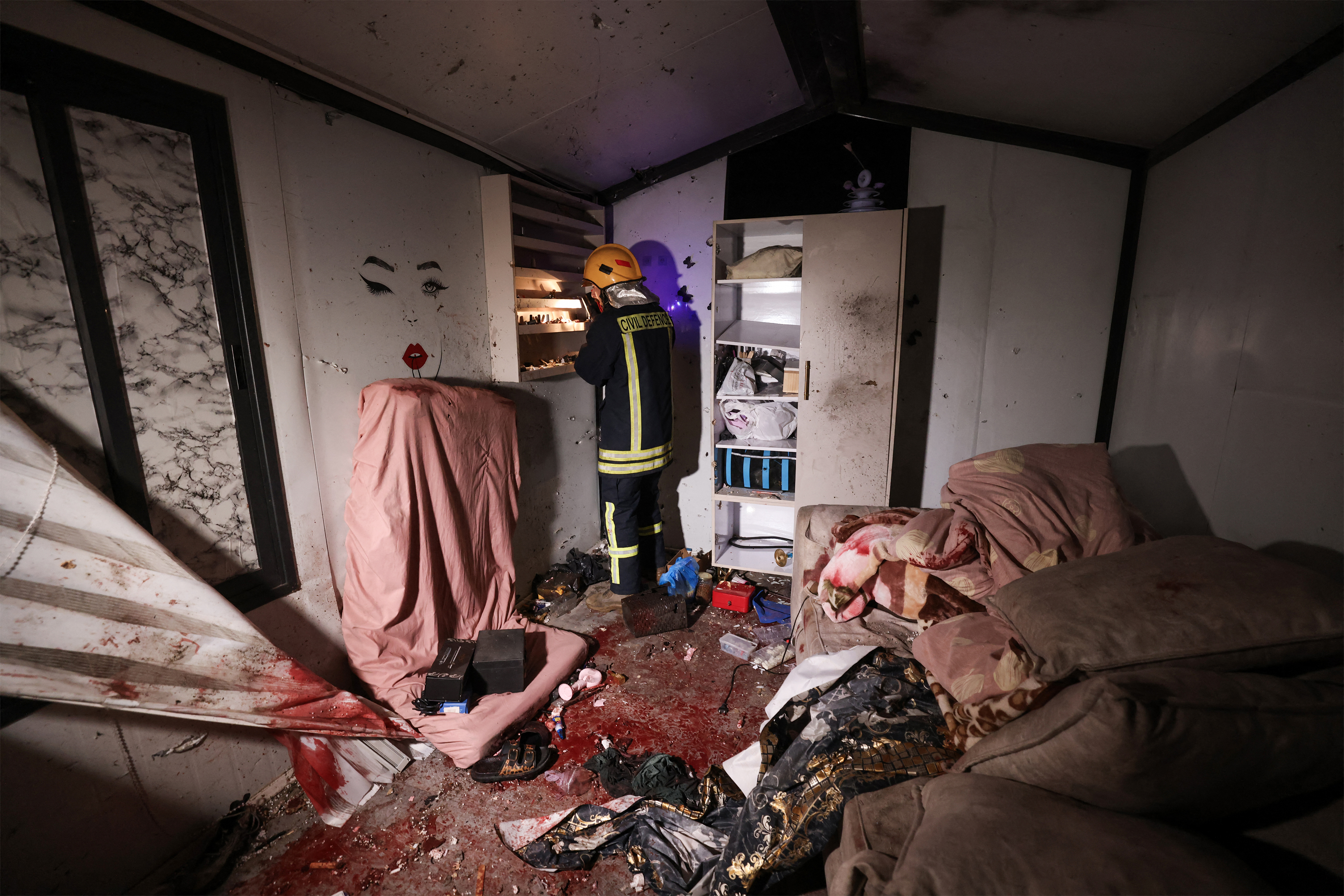 A Palestinian civil defence worker inspects the site where shrapnel from projectiles fell in Beit Awa near the Israeli-occupied West Bank city of Hebron on March 18, 2026.