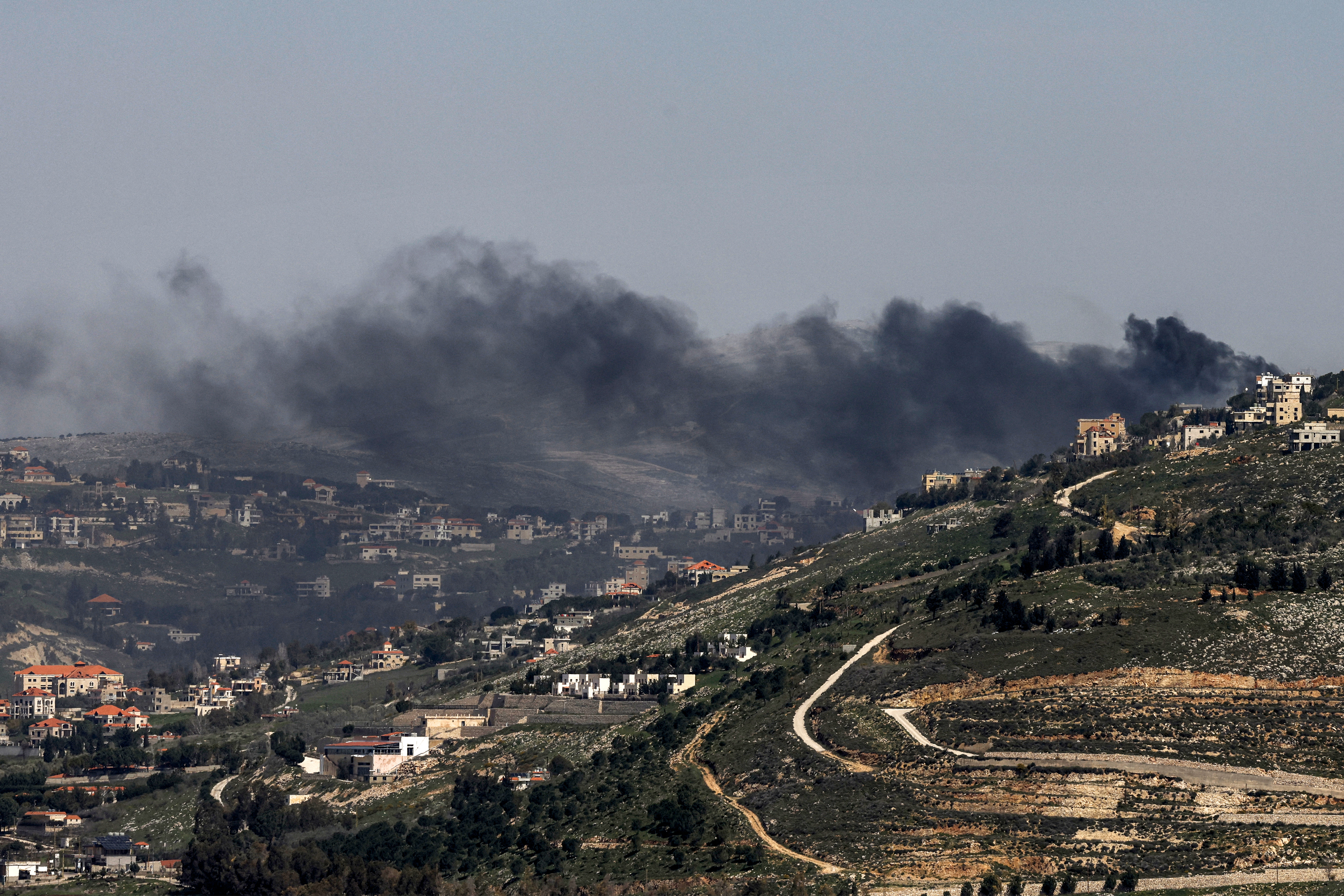 Smoke rises from villages in a mountainous area following bombardment.