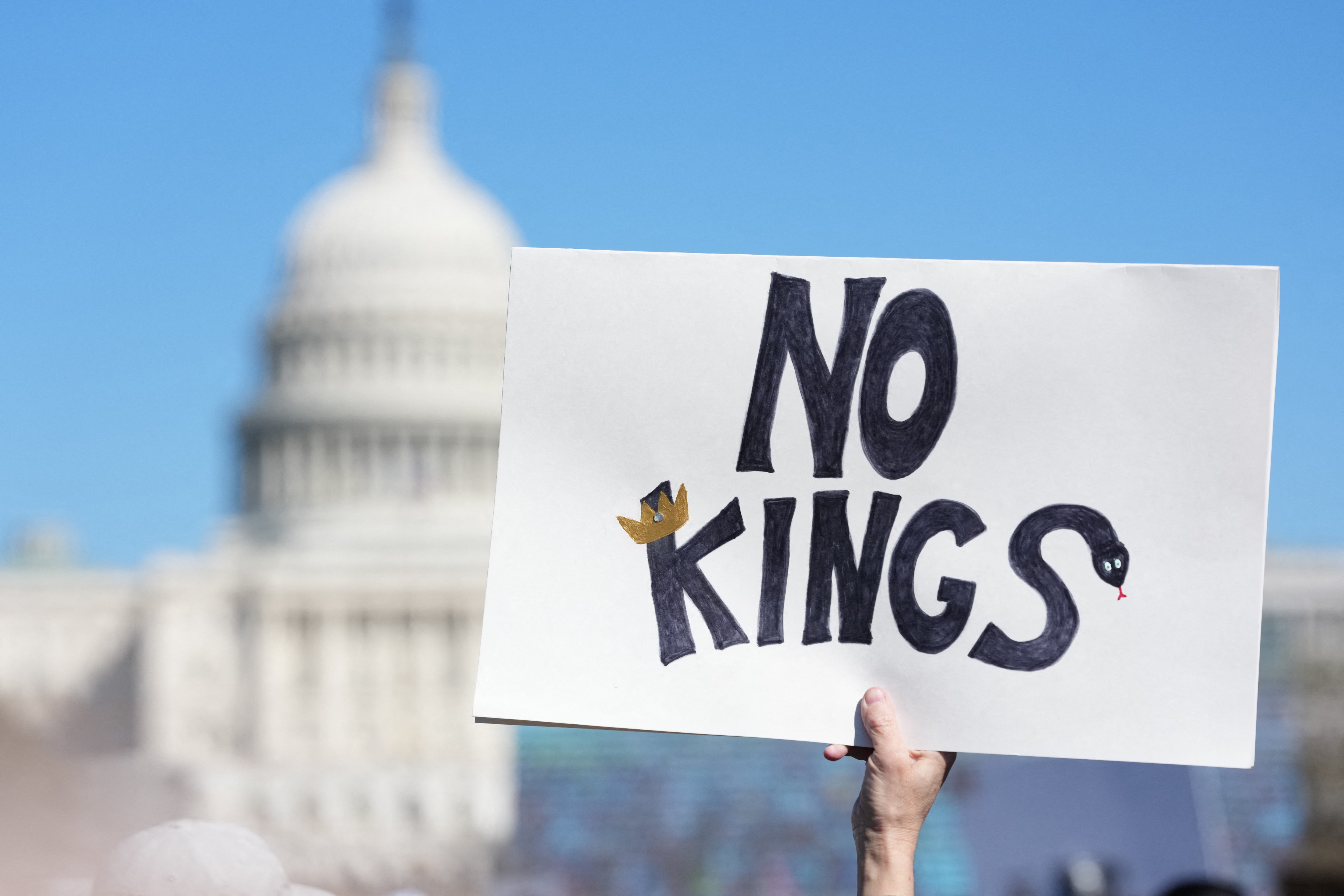A person holds up a sign reading "no kings" in front of the US Capitol during an "Impeach, Convict, Remove the Regime" rally in Washington, DC, on March 28, 2026. (Photo by Ken Cedeno / AFP)
