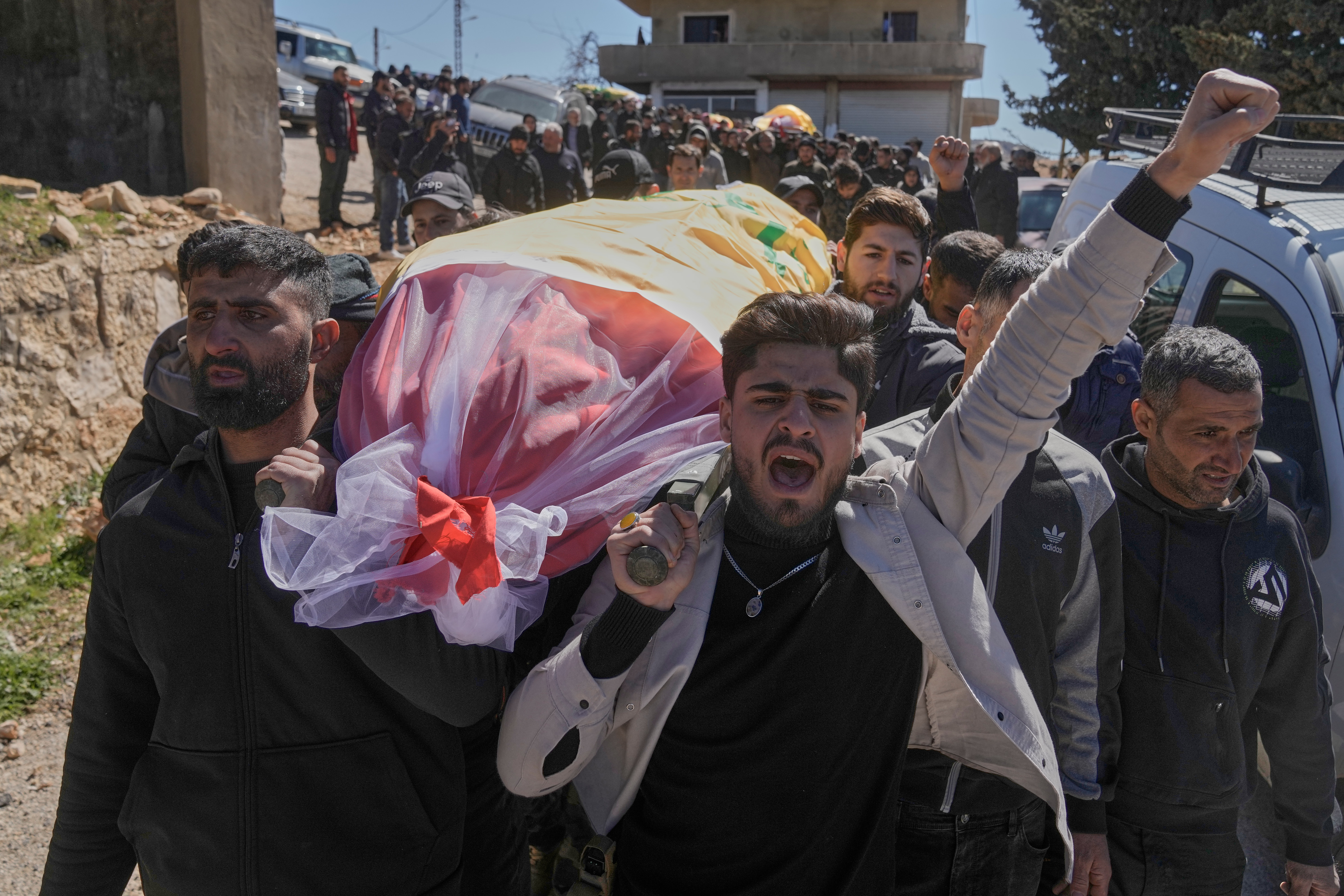 Mourners shout slogans as they carry the body of a Hezbollah fighter who was killed by Israeli airstrikes during his funeral procession in Khraibeh village, eastern Lebanon, Sunday, March 8, 2026. (AP Photo/Bilal Hussein)