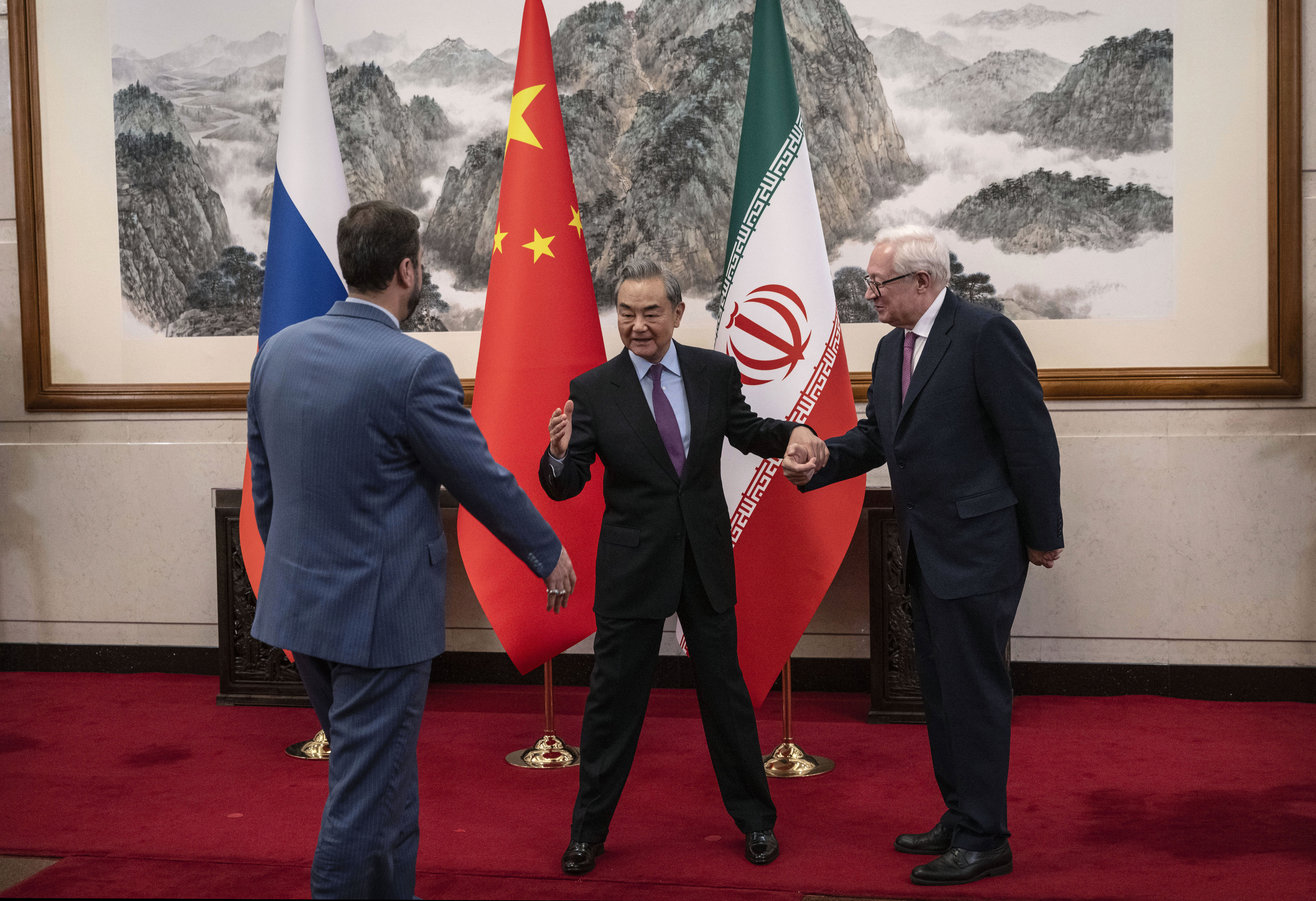 BEIJING, CHINA - MARCH 14: Chinese Foreign Minister Wag Yi,welcomes Russian Deputy Foreign Minister Sergey Ryabkov, right, and Iranian Deputy Foreign Minister Kazeem Gharibabadi, left, before a meeting regarding the Iranian nuclear issue at Diaoyutai State Guest House on March 14, 2025 in Beijing, China. (Photo by Getty Images)