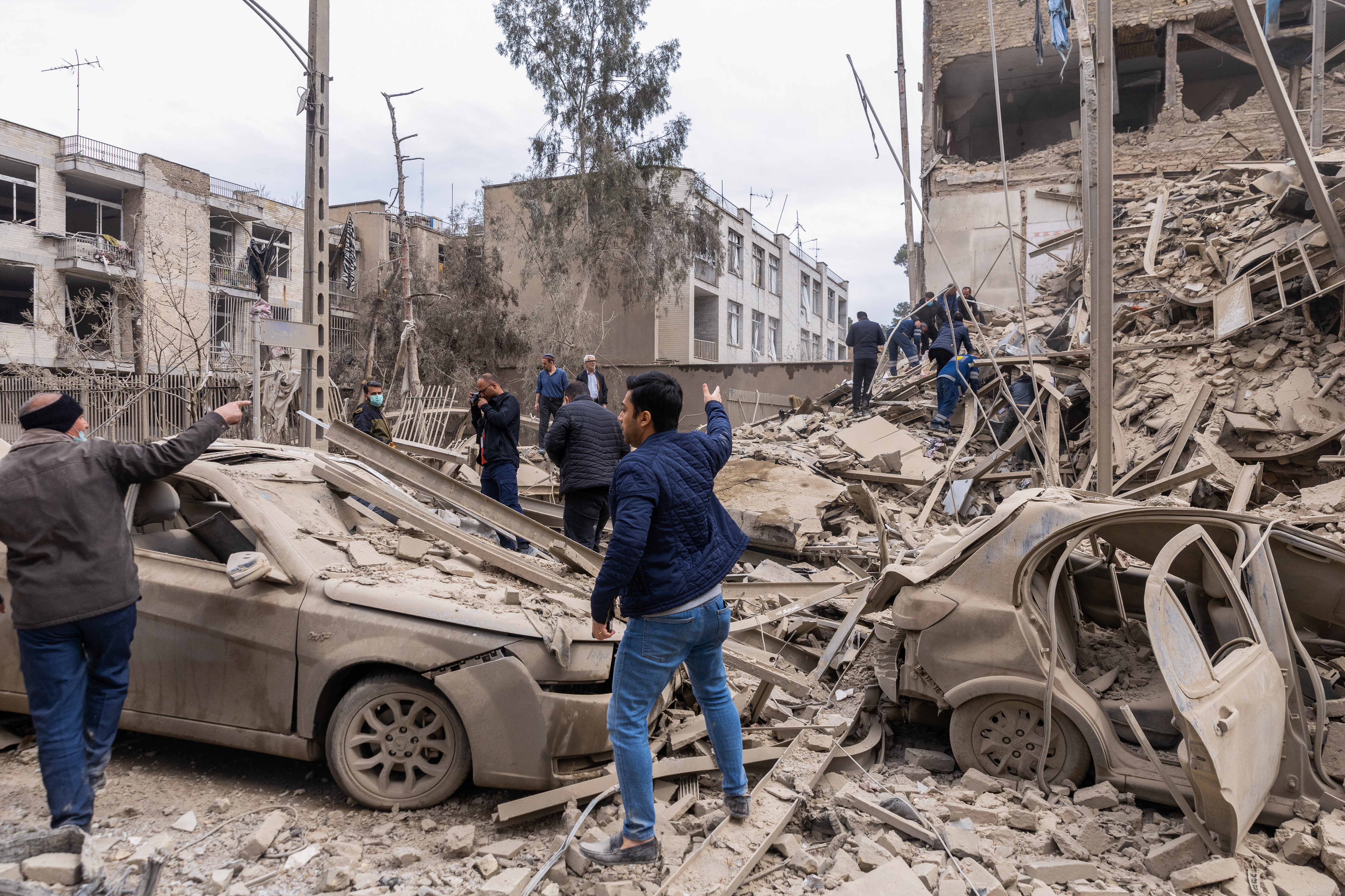 People react as emergency crews search for victims trapped in the rubble following a strike on a residential building.