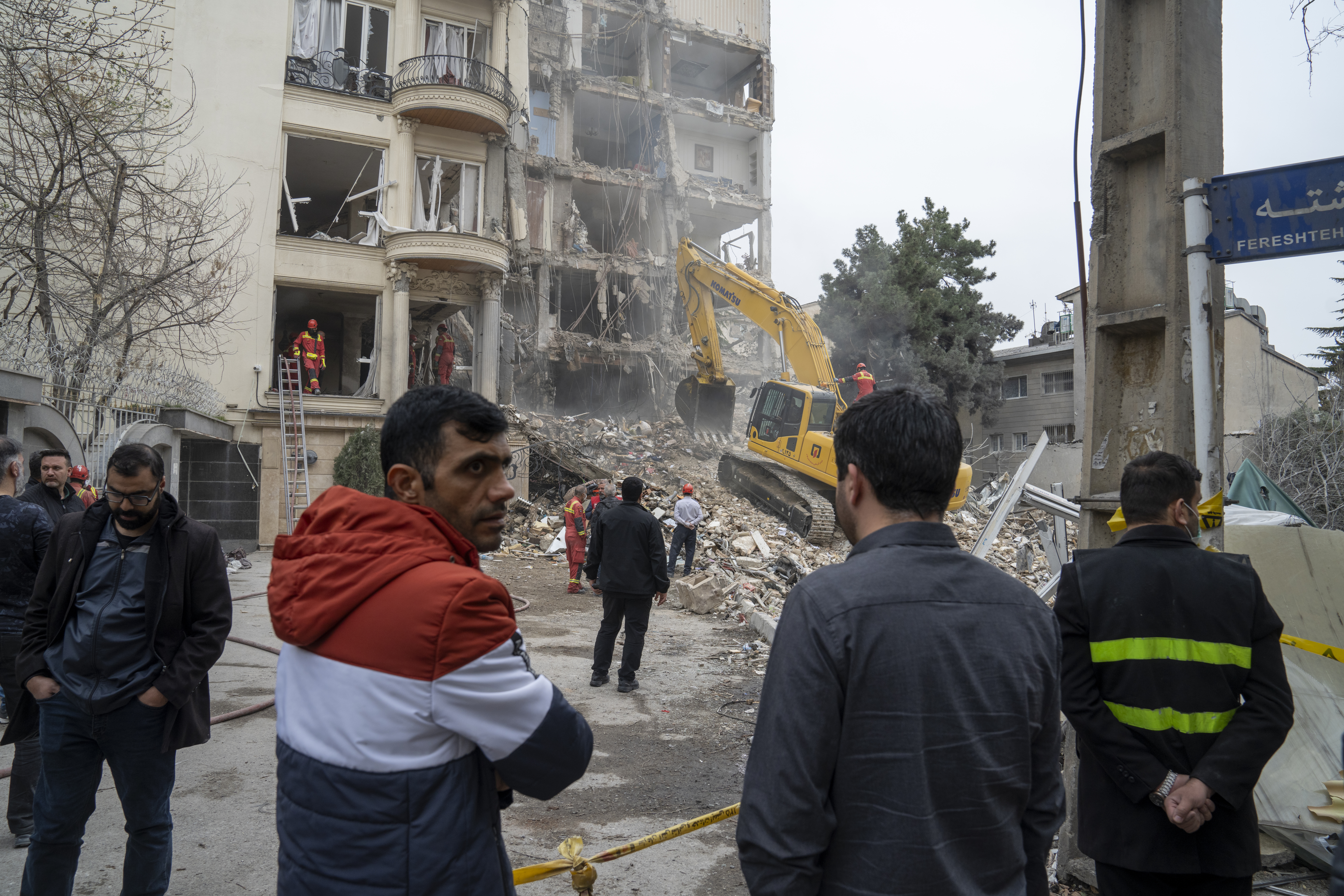 People gather near rescue workers at a destroyed building.