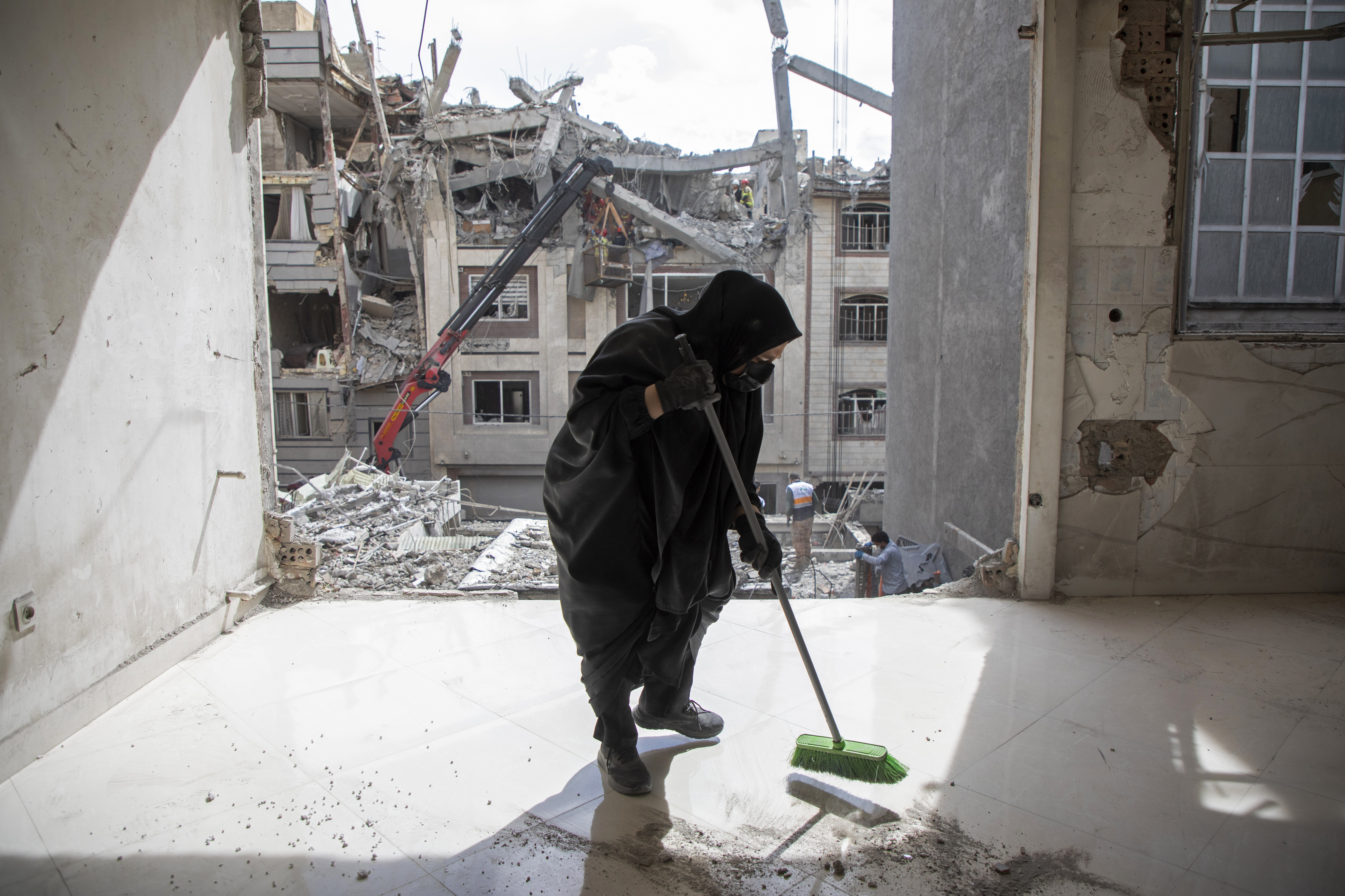 TEHRAN, IRAN - MARCH 27: A resident cleans up debris in a damaged apartment across from another residential building following an airstrike in the early hours of March 27, 2026 in Tehran, Iran. The Israeli military said that it had carried out strikes on targets across Tehran and other Iranian cities overnight. The United States and Israel have continued their joint attack on Iran that began on February 28. Iran retaliated by firing waves of missiles and drones at Israel and U.S. allies in the region, while also effectively blockading the Strait of Hormuz, a critical shipping route. (Photo by Majid Saeedi/Getty Images)
