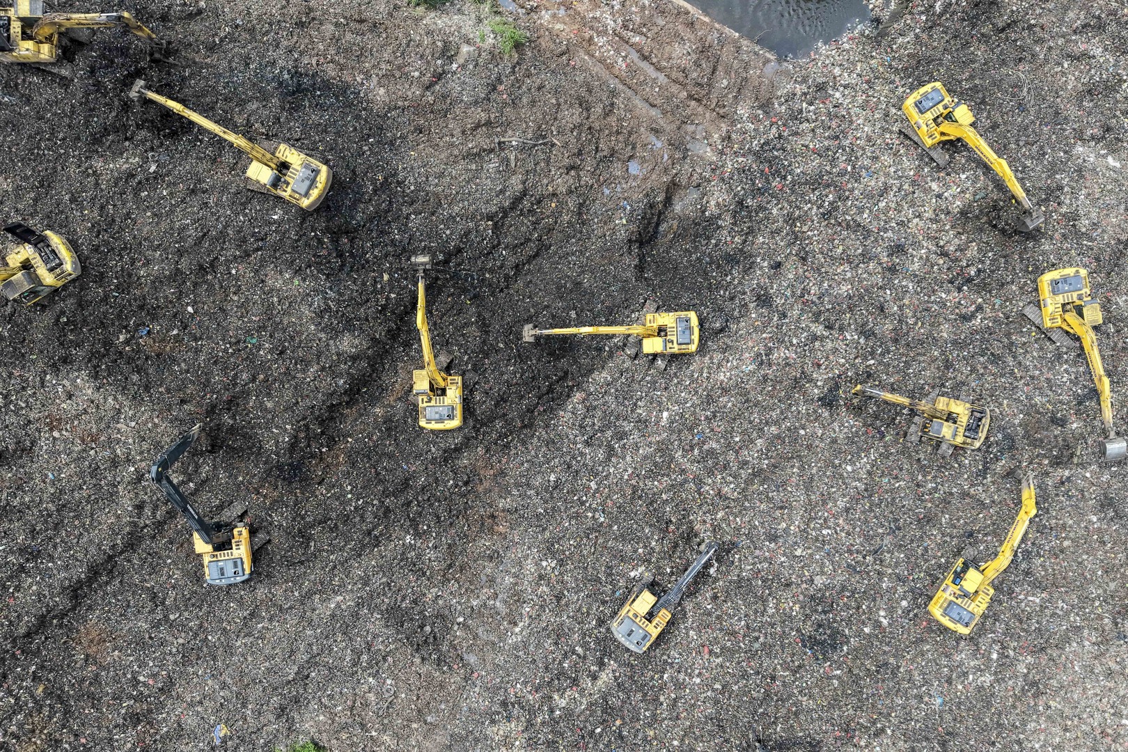 This aerial picture shows a rescue team using heavy machinery to search for people following a landslide at Bantargebang landfill in Bekasi, West Java, on March 9, 2026. A landslide on Indonesia's biggest landfill buried trucks and food stalls, killing four people, rescuers said on March 9 as they searched for at least five more reported missing. [Bay Ismoyo/AFP]