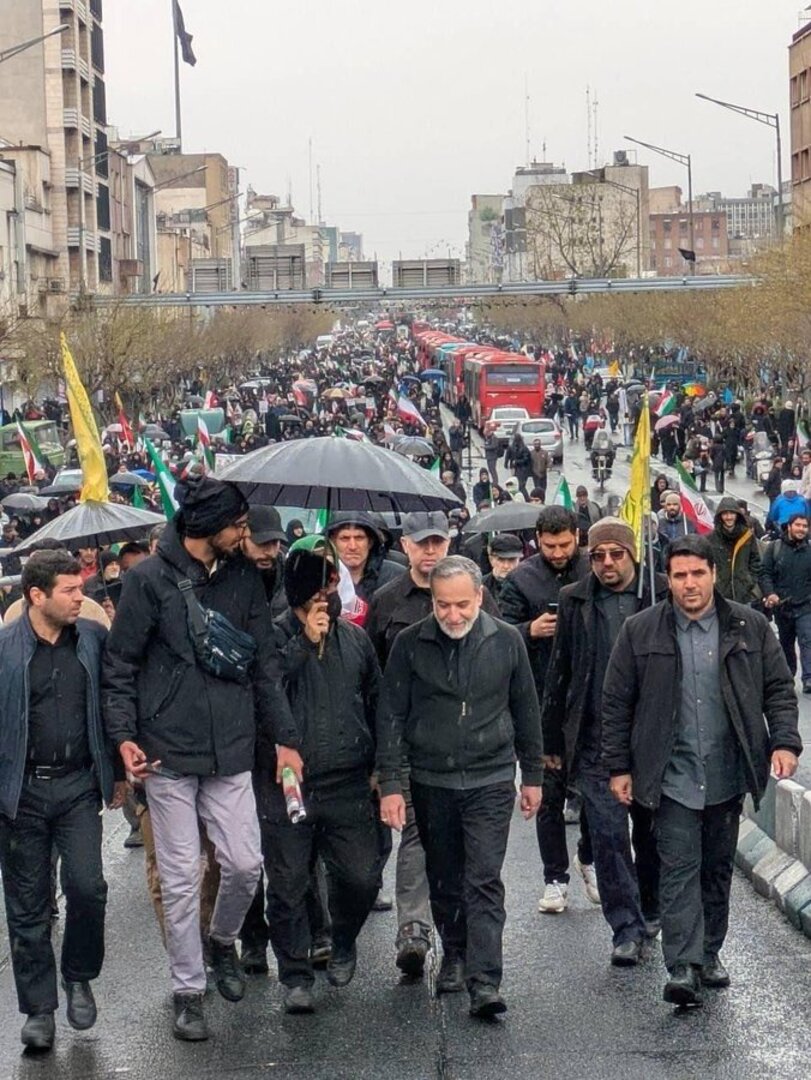 A photo posted to Iranian Foreign Minister Abbas Araghchi's X account shows him flanked by supporters marching through the streets of Tehran on March 13, 2026 to celebrate Quds Day, as American Defense Secretary Pete Hegseth claimed the Islamic Republic's top leadership was hiding like "rats" as US-Israeli airstrikes continued to pound the country. [Abbas Araghchi/X]