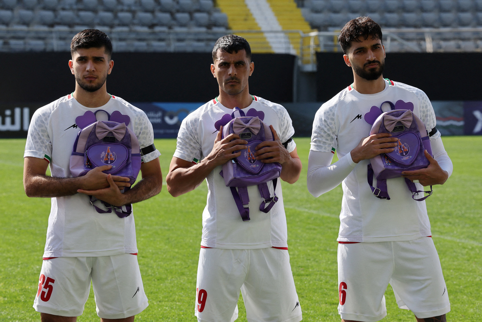 Iranian football players Aria Yousefi, Ali Nemati, and Mohammad Ghorbani hold school bags in memory of the victims of the girls school bombing in Minab, Iran ahead of a friendly match against Nigeria at Mardan Sports Complex in Antalya, Turkey on March 27, 2026. [Umit Bektas/Reuters]
