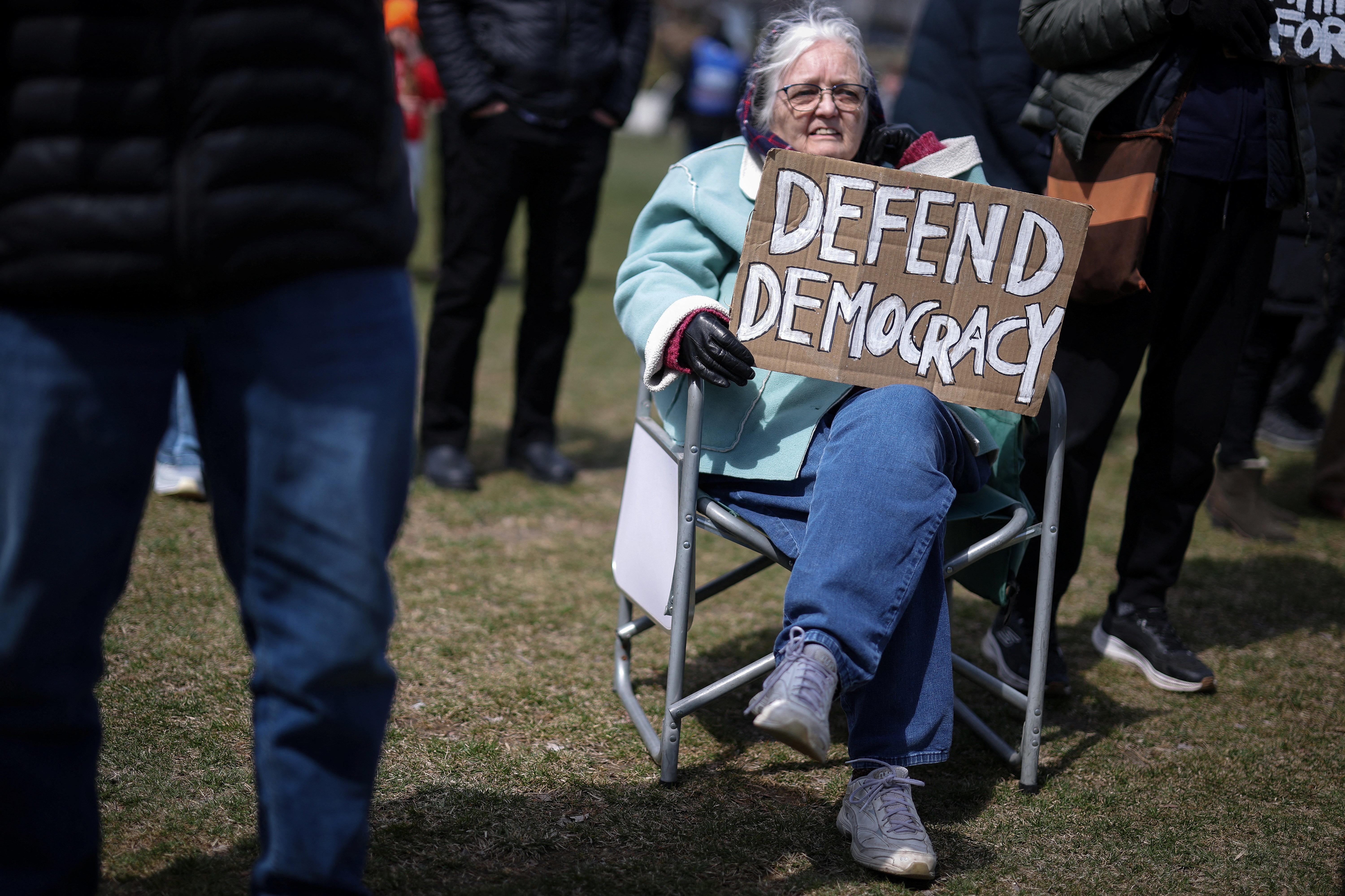 79-year-old Christine Hughes holds a sign as she attends a demonstration during the day of "No Kings" protests against U.S. President Donald Trump's administration policies, in the New York City suburb of Nyack, New York, U.S., March 28, 2026. REUTERS/Mike Segar