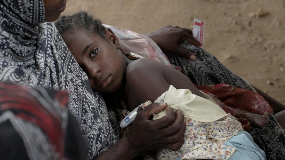 A woman holds her sick daughter as she receives medical help