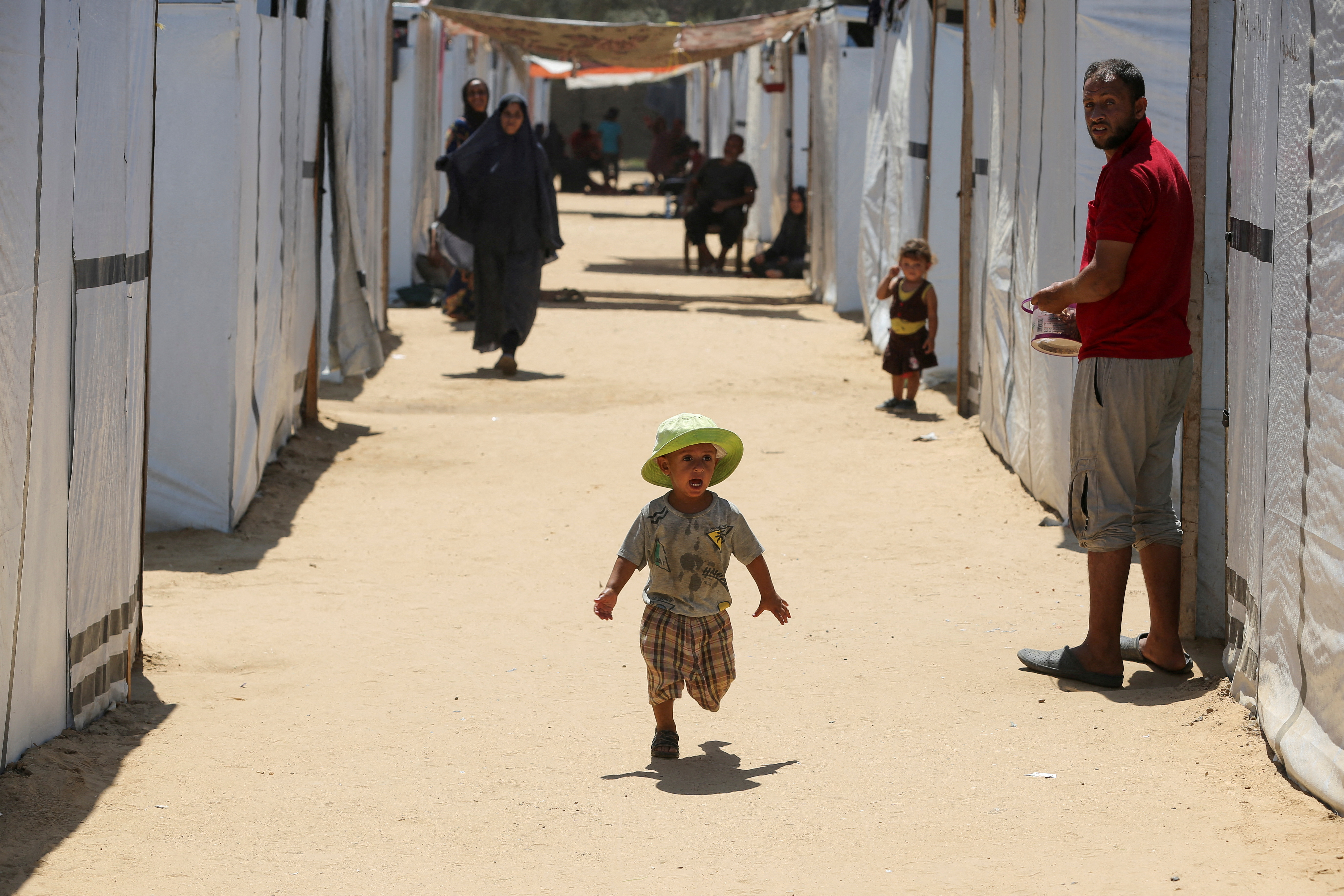A displaced Palestinian boy runs in a tent camp designated for people with special needs, amid the Israel-Hamas conflict, in Deir Al-Balah in the central Gaza Strip August 8, 2024. REUTERS/Hatem Khaled REFILE - CORRECTING INFORMATION FROM "A BOY RUNS WITH AN AMPUTATED LEG" TO "A BOY RUNS