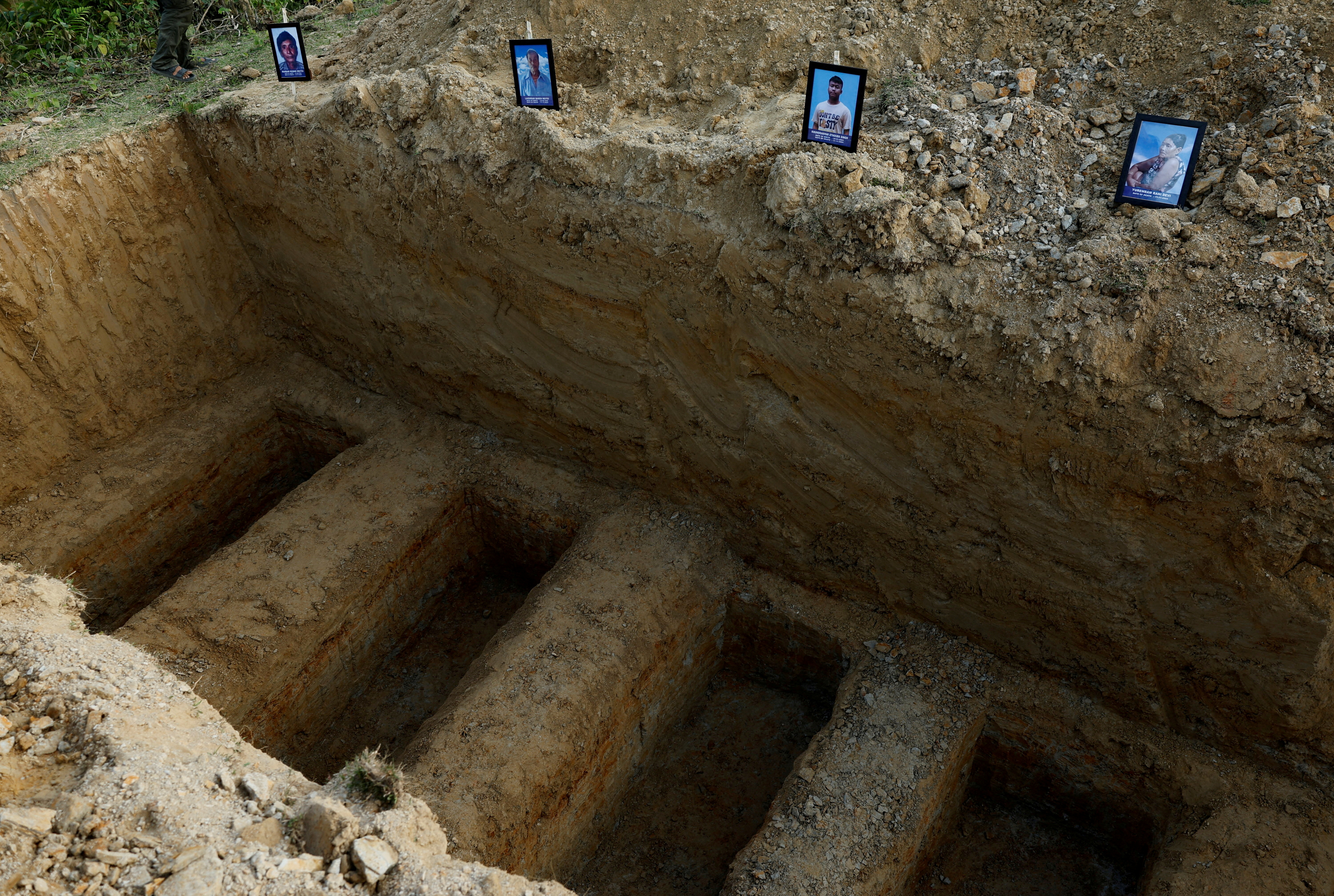 Photographs of deceased Meiteis who were killed after ethnic violence broke out in Borobekra are placed next to graves dug for their funeral, in Jiribam in the northeastern state of Manipur, India, November 22, 2024