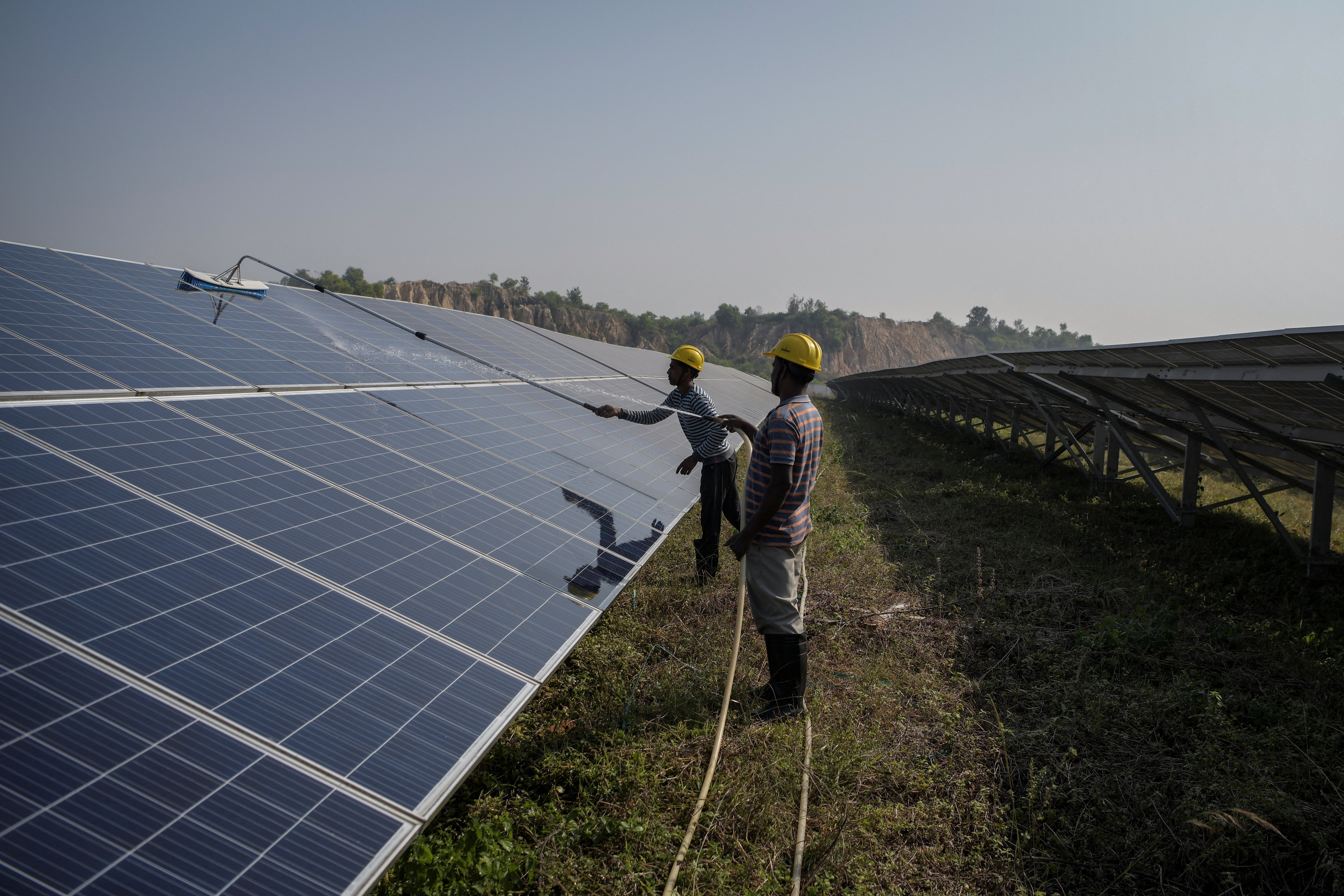 Workers clean installed solar panels.