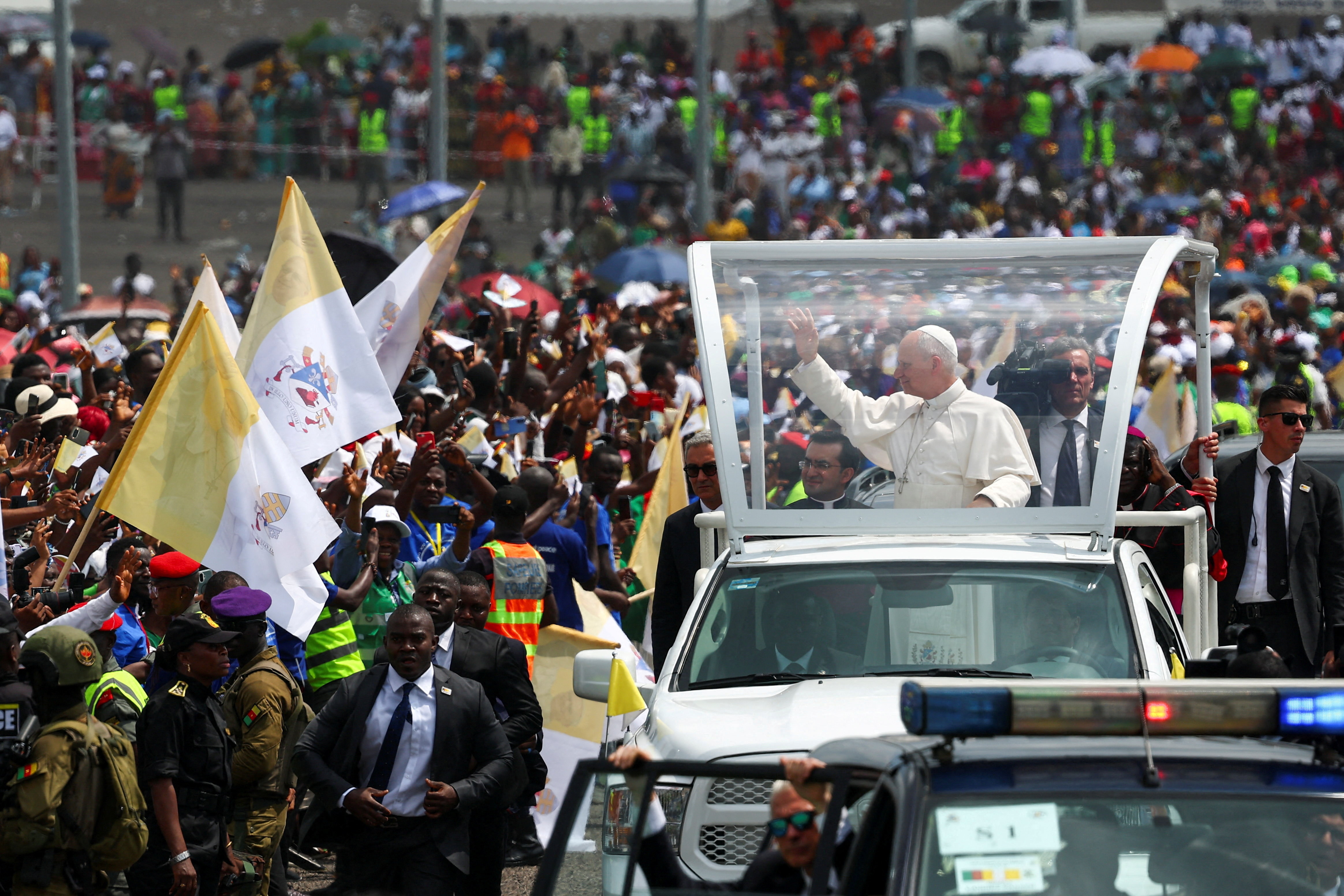 Pope Leo XIV greets people as he arrives in his vehicle to hold a holy Mass.