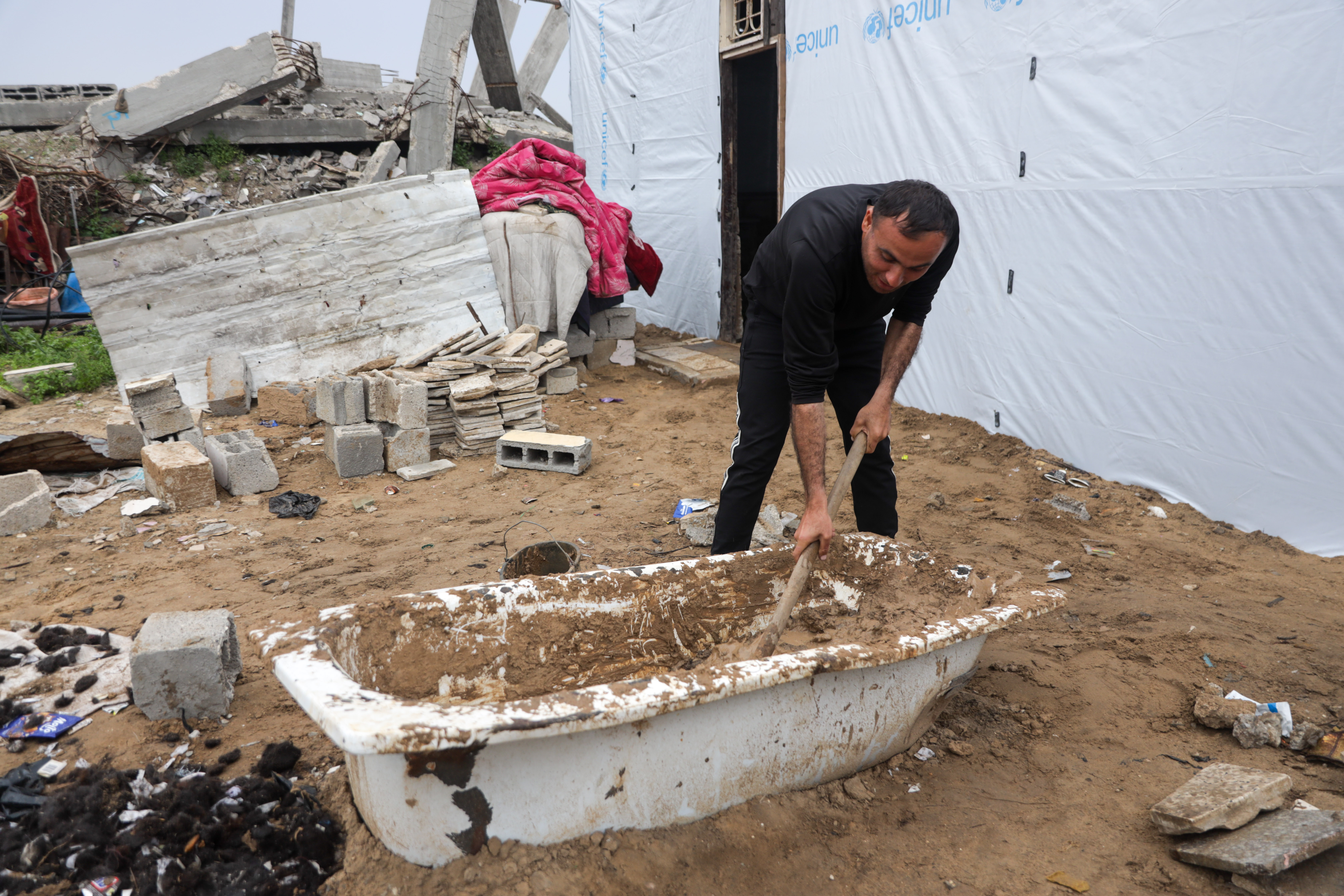 Man mixes mud with hair in a bathtub