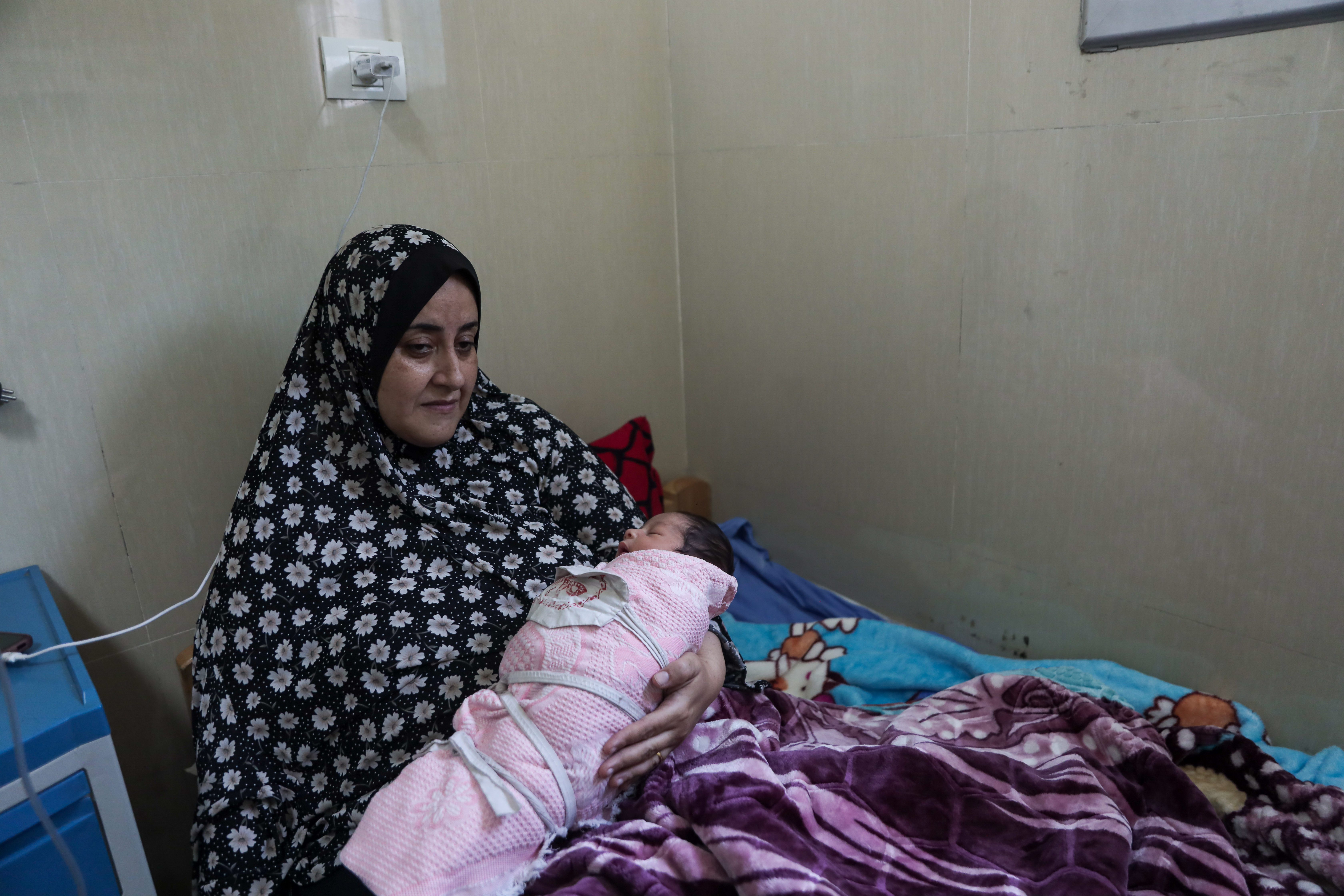 Sanaa Al-Shukri holds her newborn child as she lies in a hospital bed