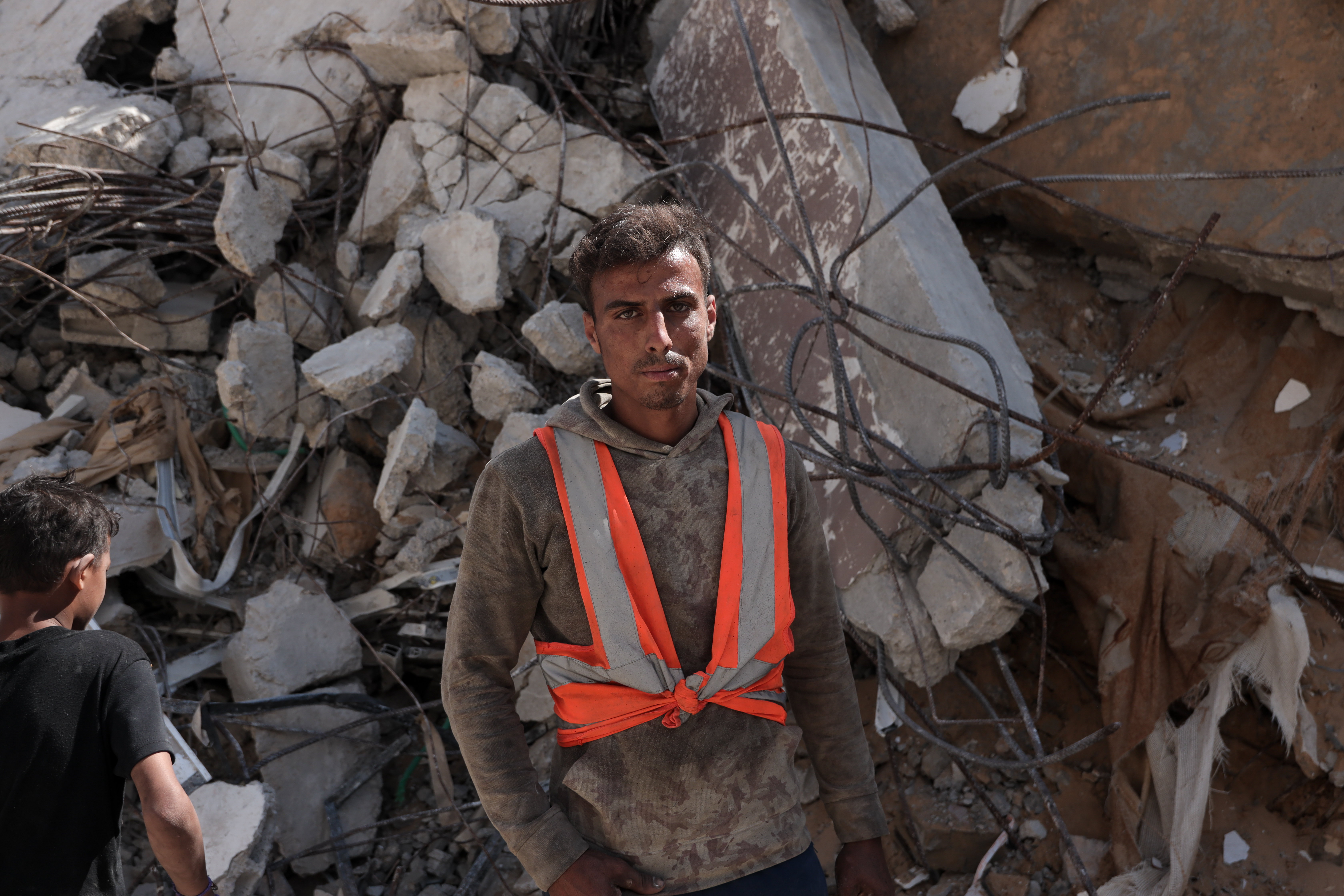 Ibrahim stands before a pile of rubble