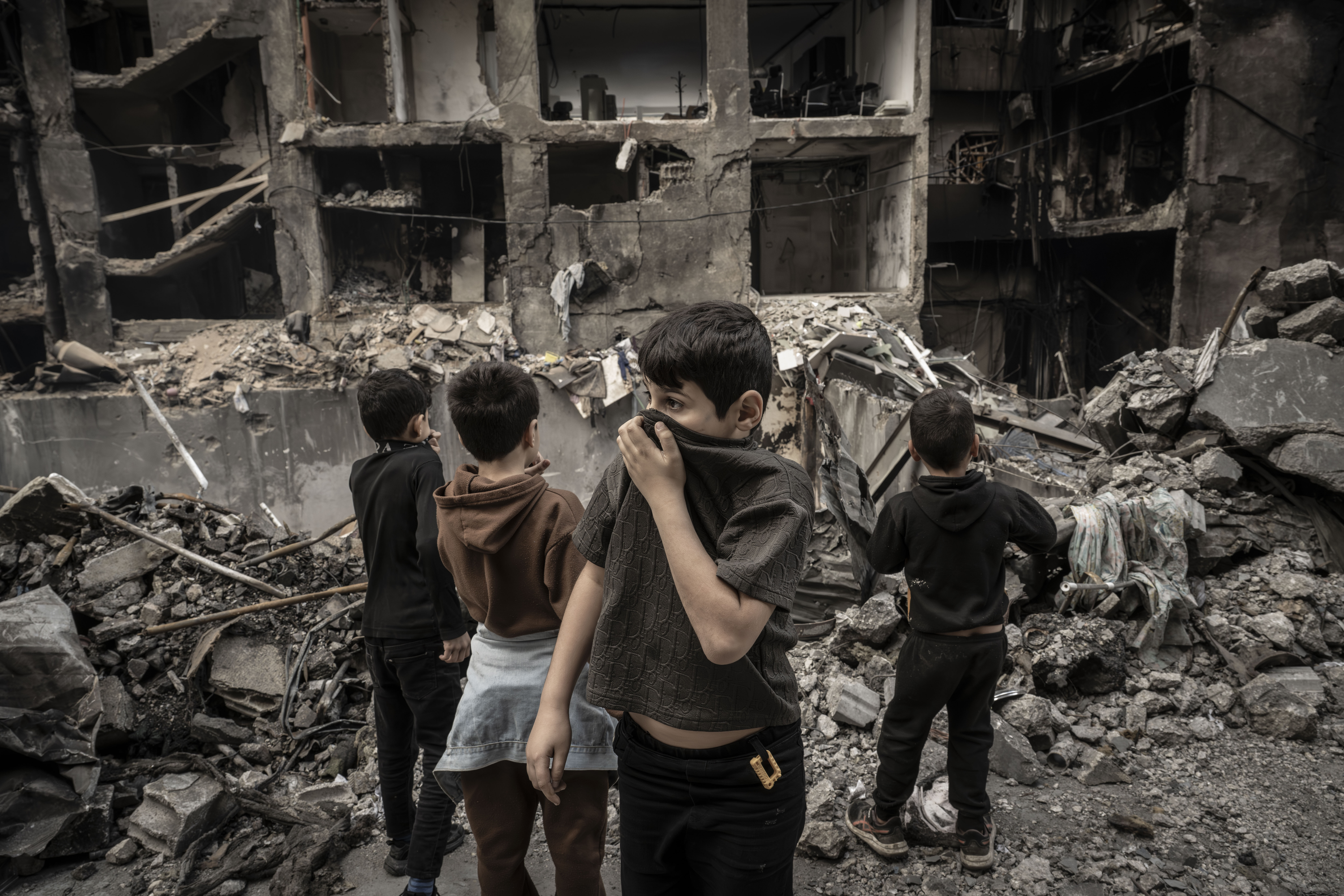 Children try to protect themselves from dust and smoke rising from the rubble where a large-scale destruction caused by Israeli airstrikes targeting the Corniche al-Mazraa area in the capital Beirut, Lebanon