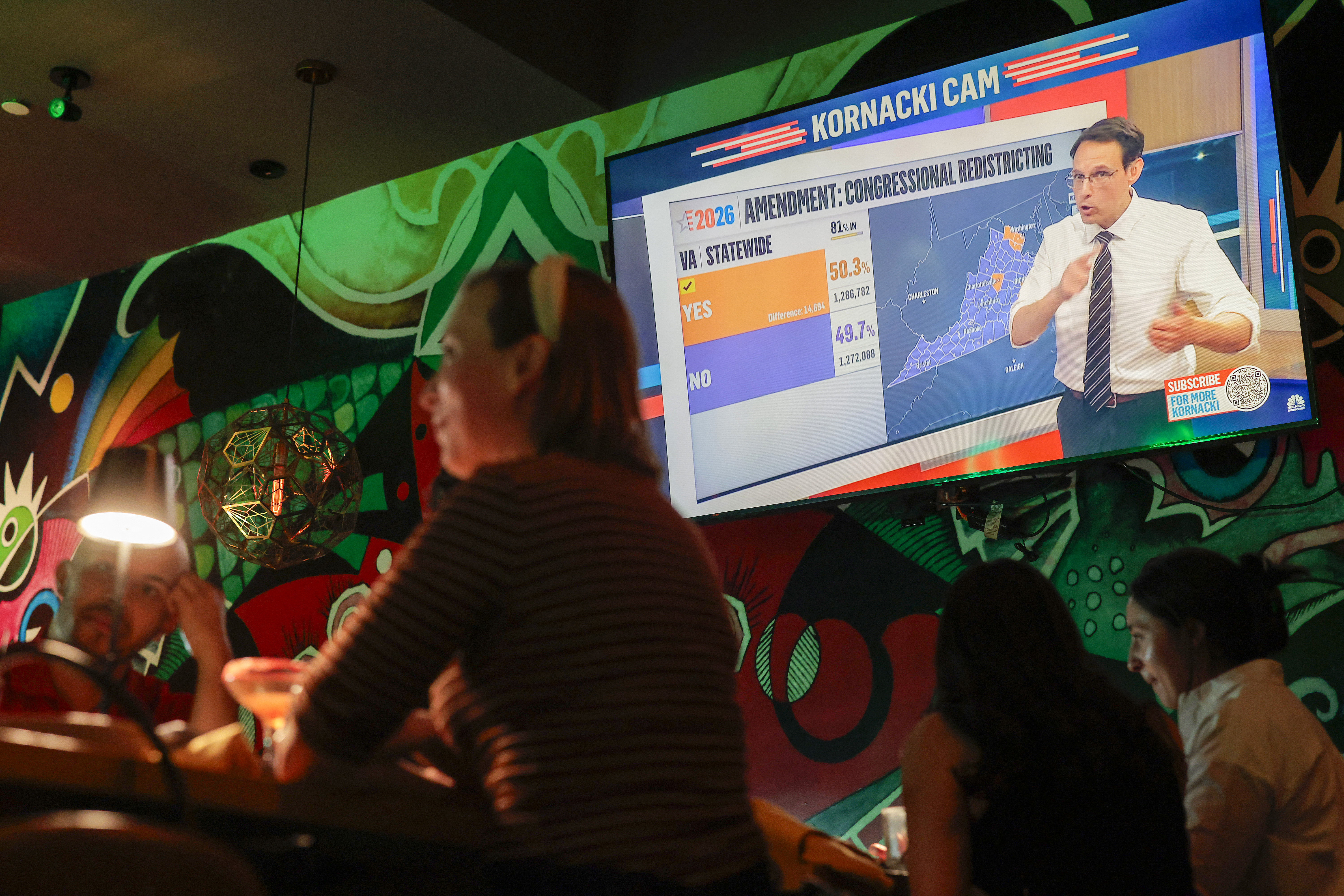 People attend a watch party in front of a big TV screen.