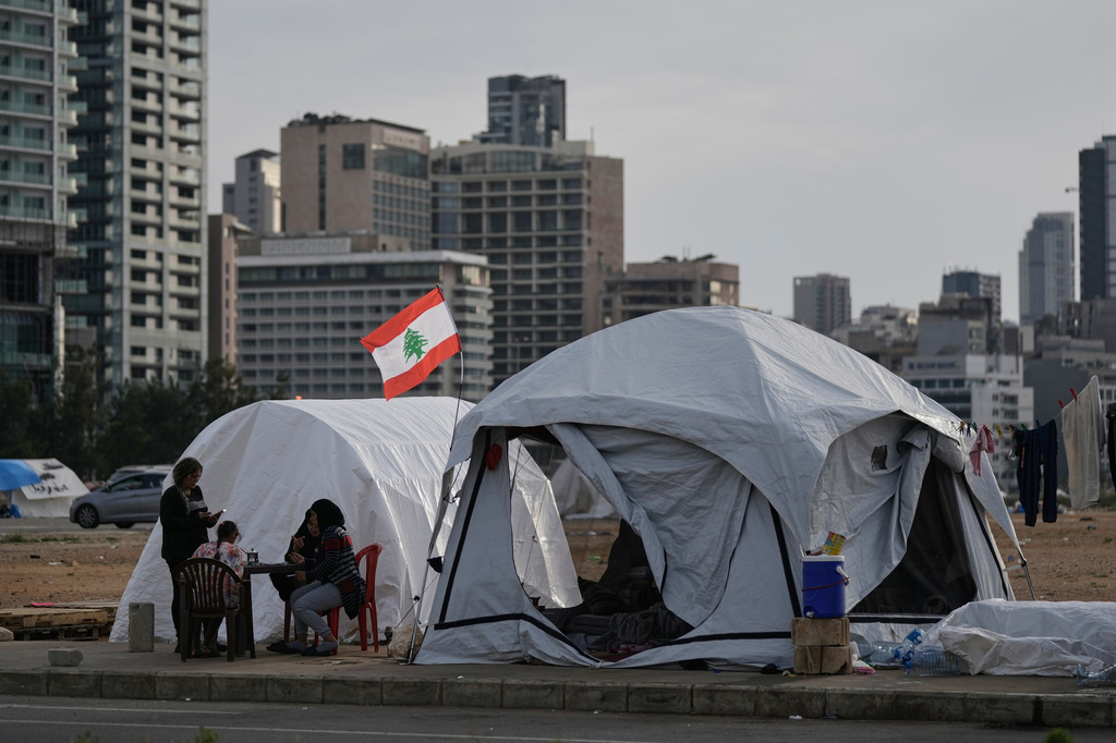 Displaced people who fled Israeli strikes in southern Lebanon sit outside shelter tents in Beirut, Lebanon