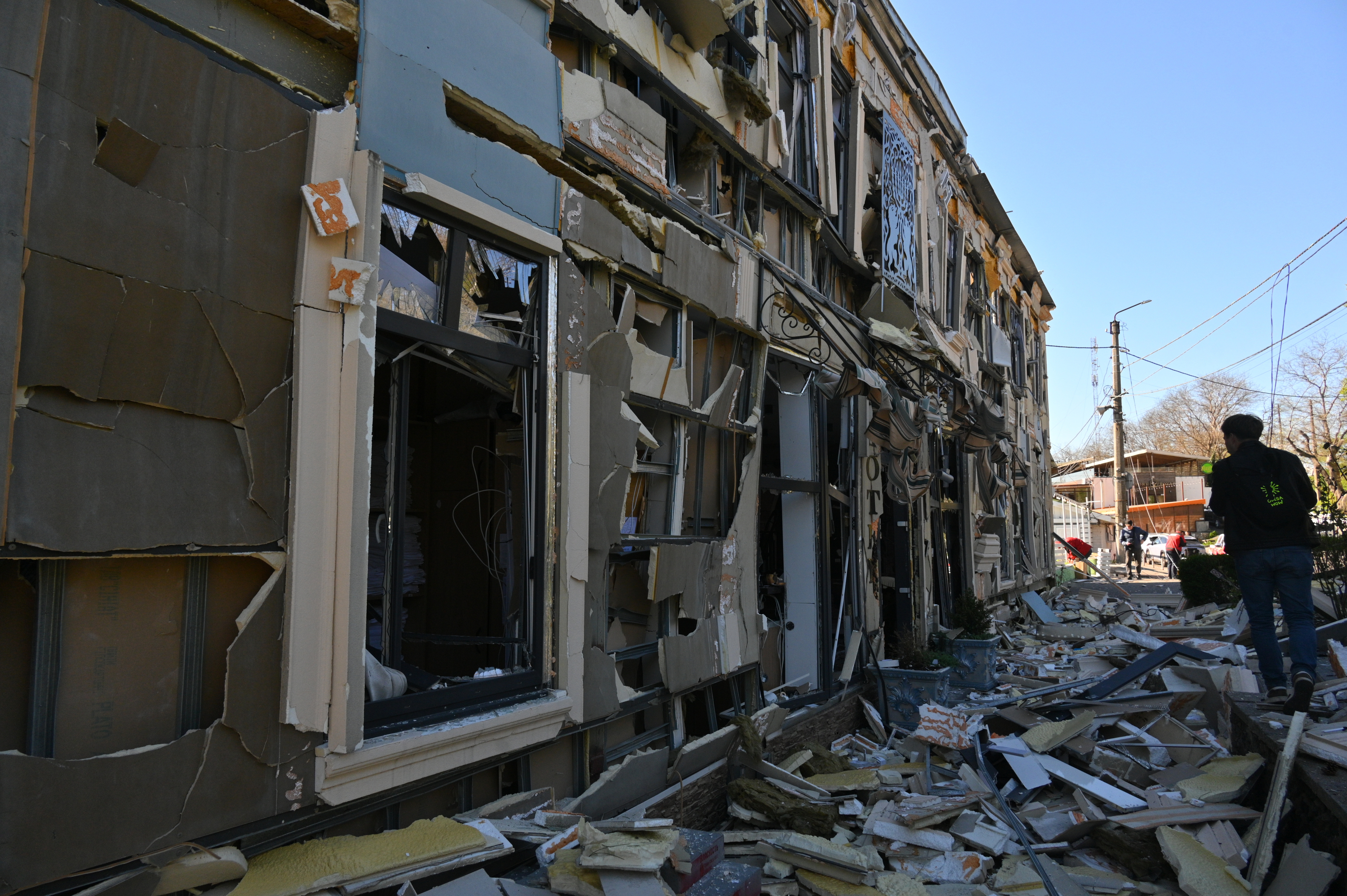 A person walks near houses damaged by attacks.