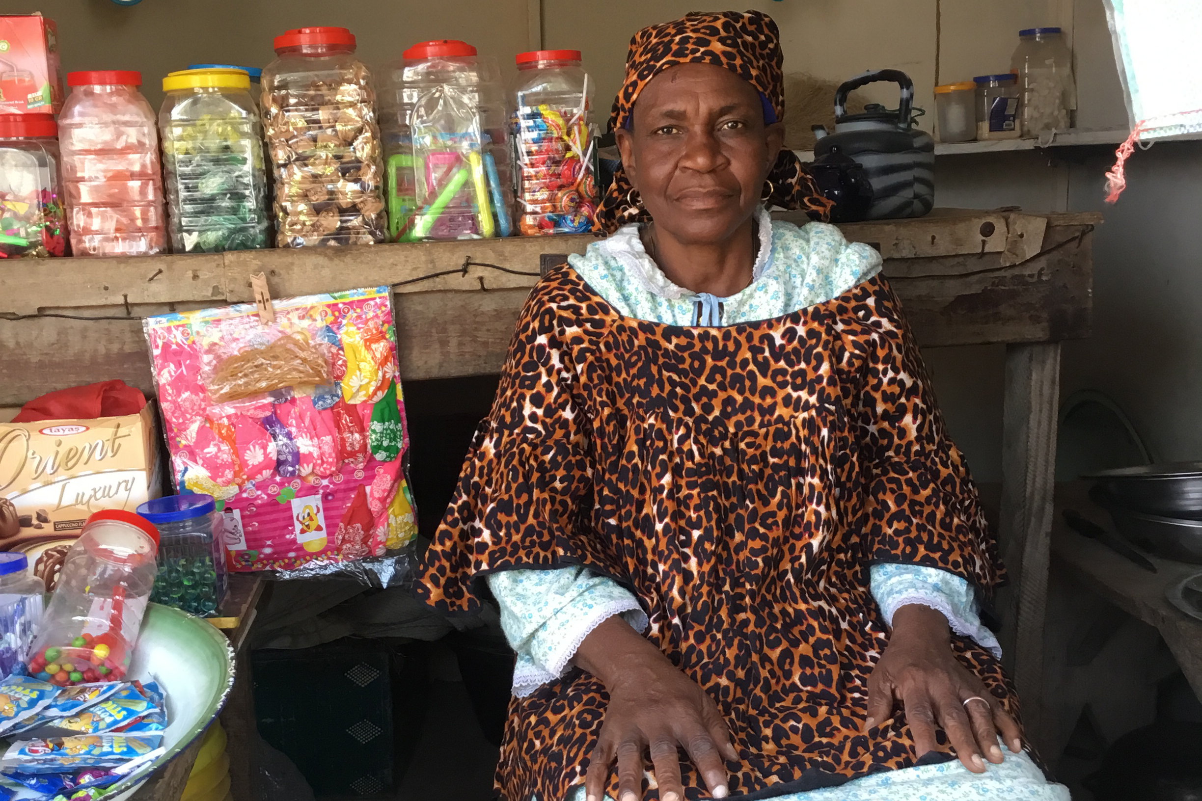 Amina Issaka sits inside her small shop, where she sells cooking ingredients and children’s clothing. Without the required documentation, she is unable to formally register the business