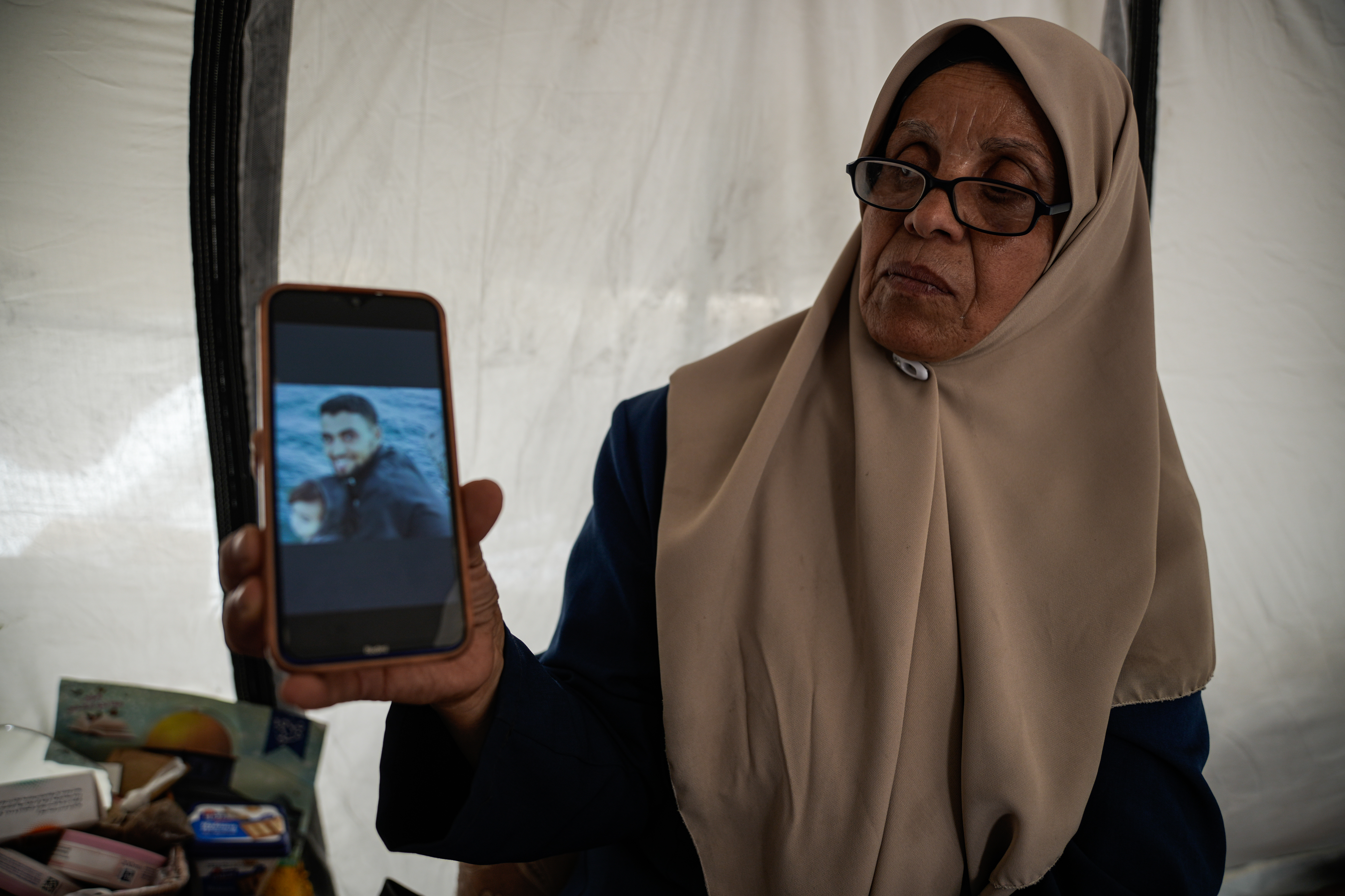 Ina’am Al-Dahdouh holds the photo of her eldest detained son, Mahmoud, at her tent in Tal el hawwa southwest of Gaza city [Omar Ashtawy/ Al Jazeera]