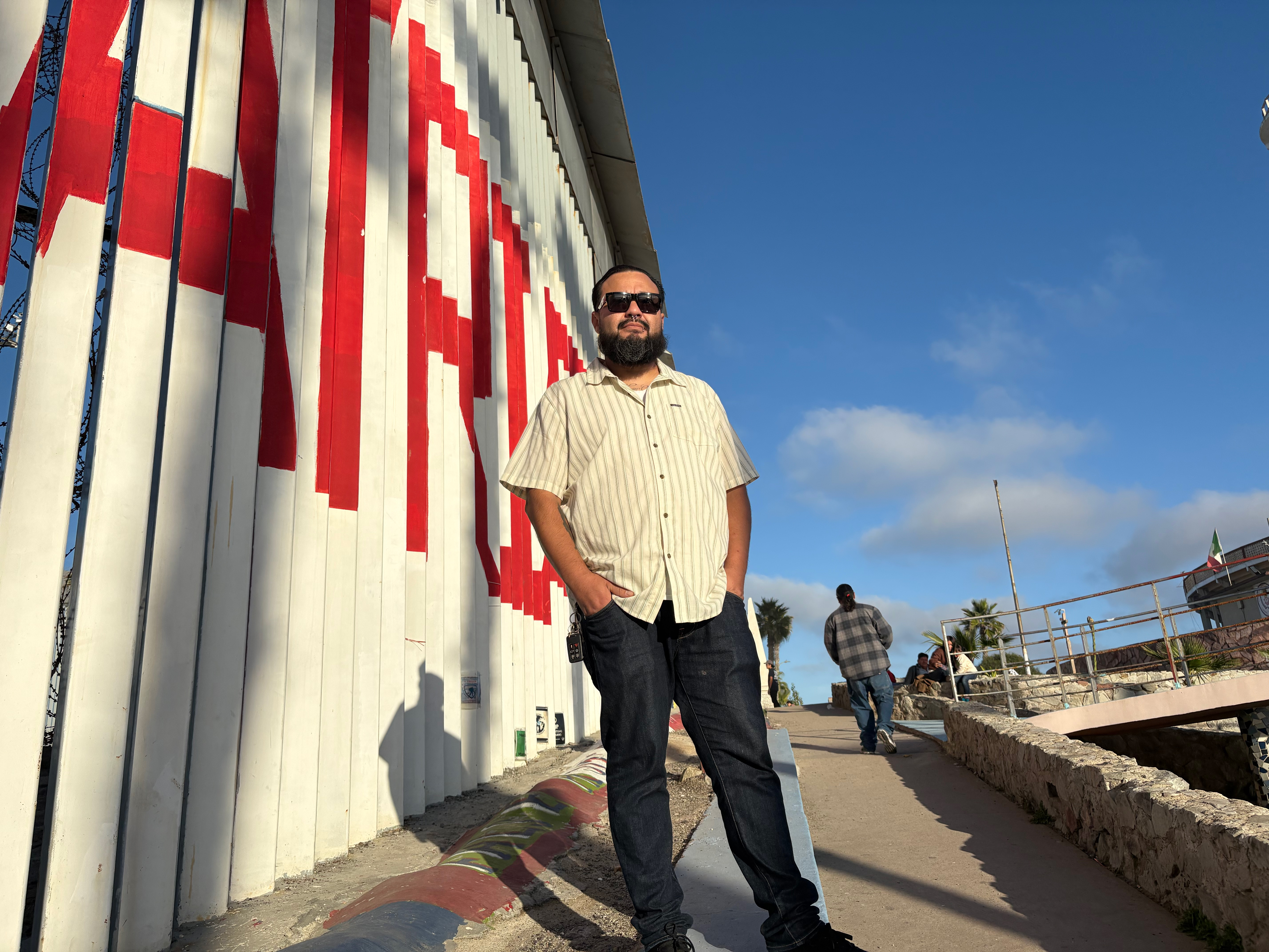 Edwin Salgado next to the US-Mexico border wall