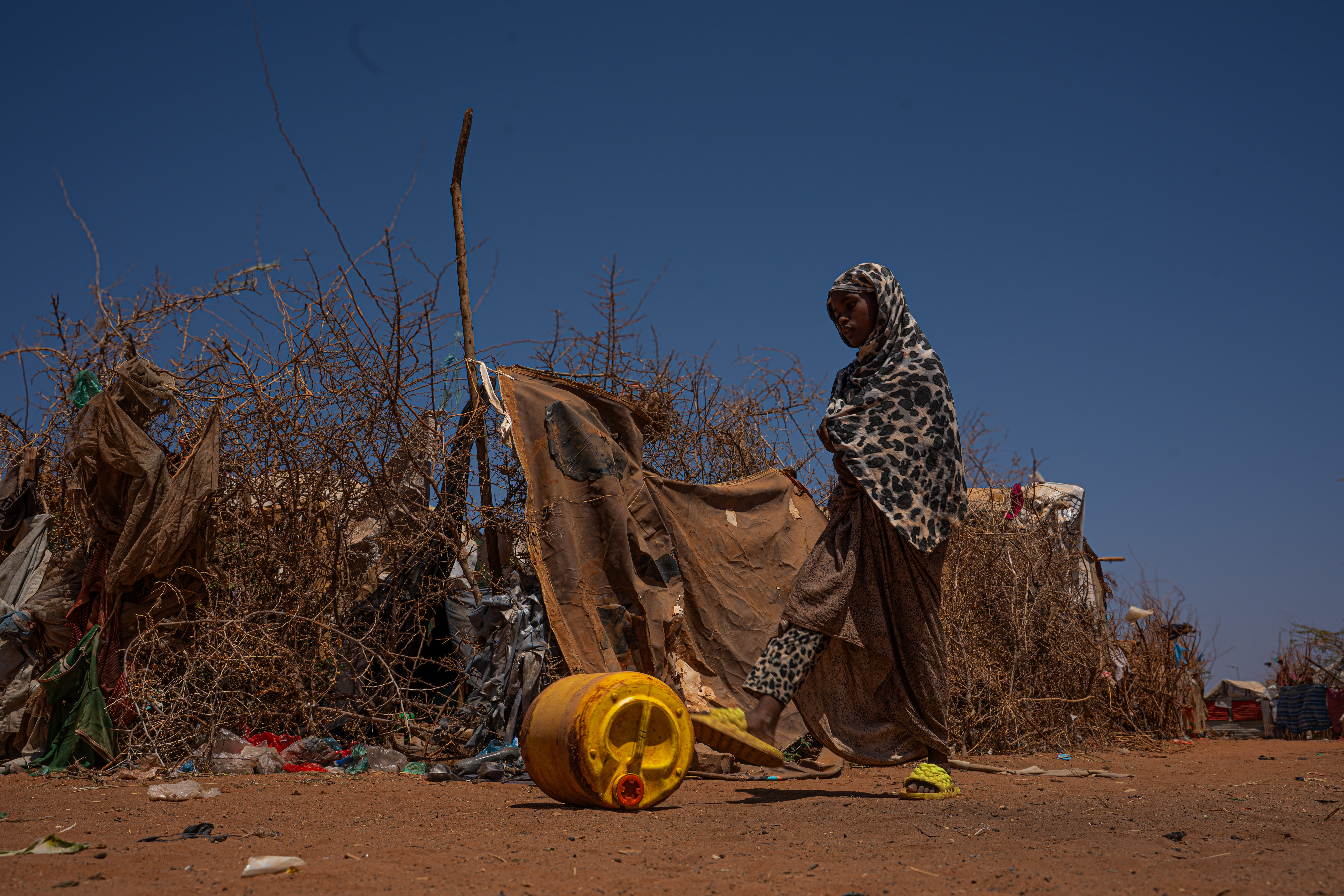 Hawa Ali Abdi is a 13 year old young girl displaced by drought, lives with her family in Kabasa camp in Dollow. Each day she walks long distances to collect water from the nearest water point, a journey that takes hours under the scorching sun. Like many displaced children in Somalia's camps, her education has been suspended. Survival has taken the place of school. Kabasa camp, Dollow, Gedo region, Somalia. [Abdulkadir Mohamed/NRC]